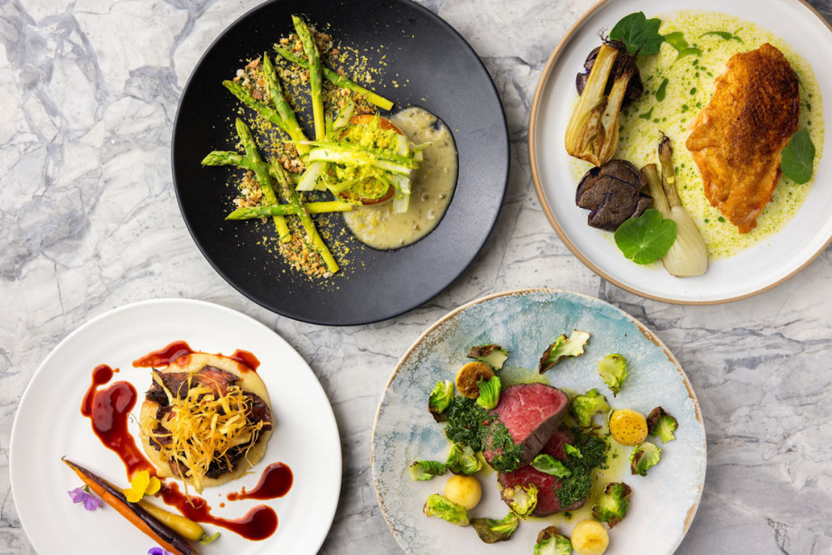 A bunch of plates of food sitting on a nice marble counter