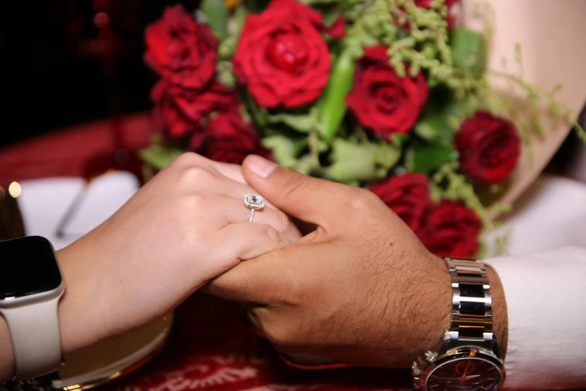 A couple holding hands with a diamond ring on a finger