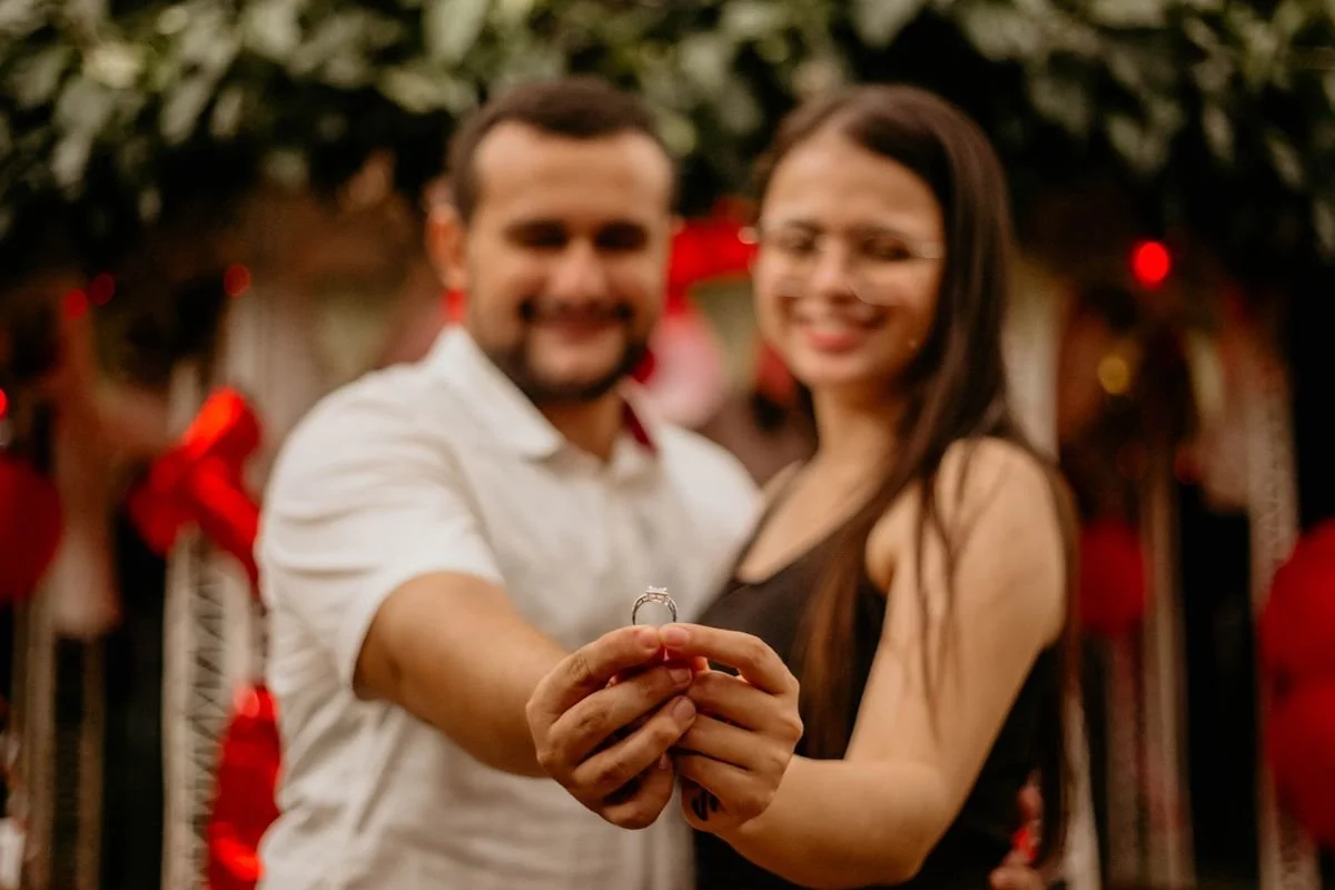 A couple holding a ring in front of the camera