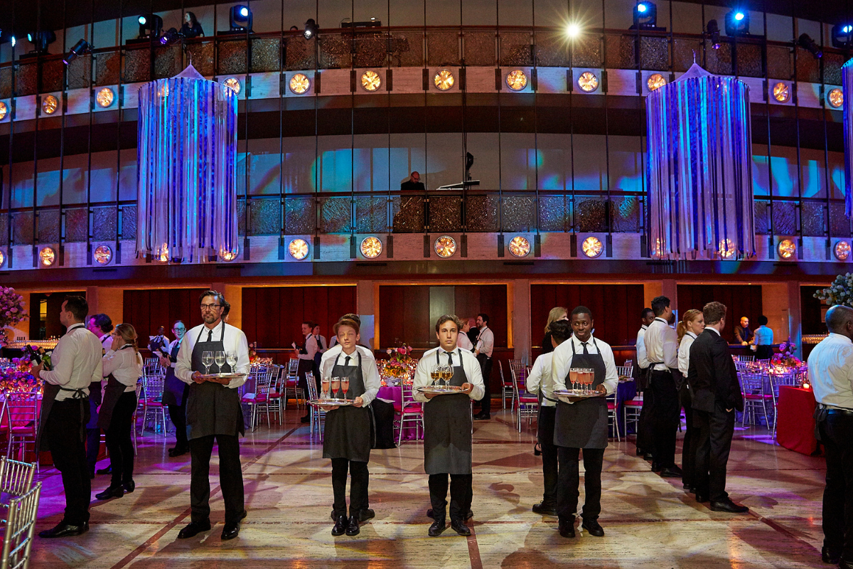 A bunch of servers holding wine glasses and ready to serve
