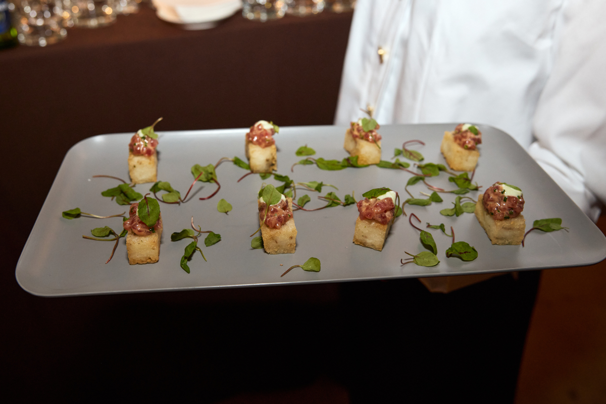 A server holding a platter of bread and meats