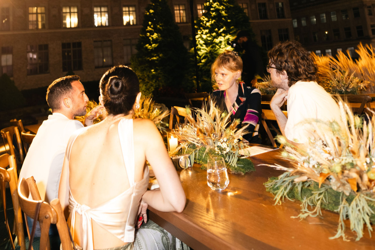 4 people sitting at a table outside talking