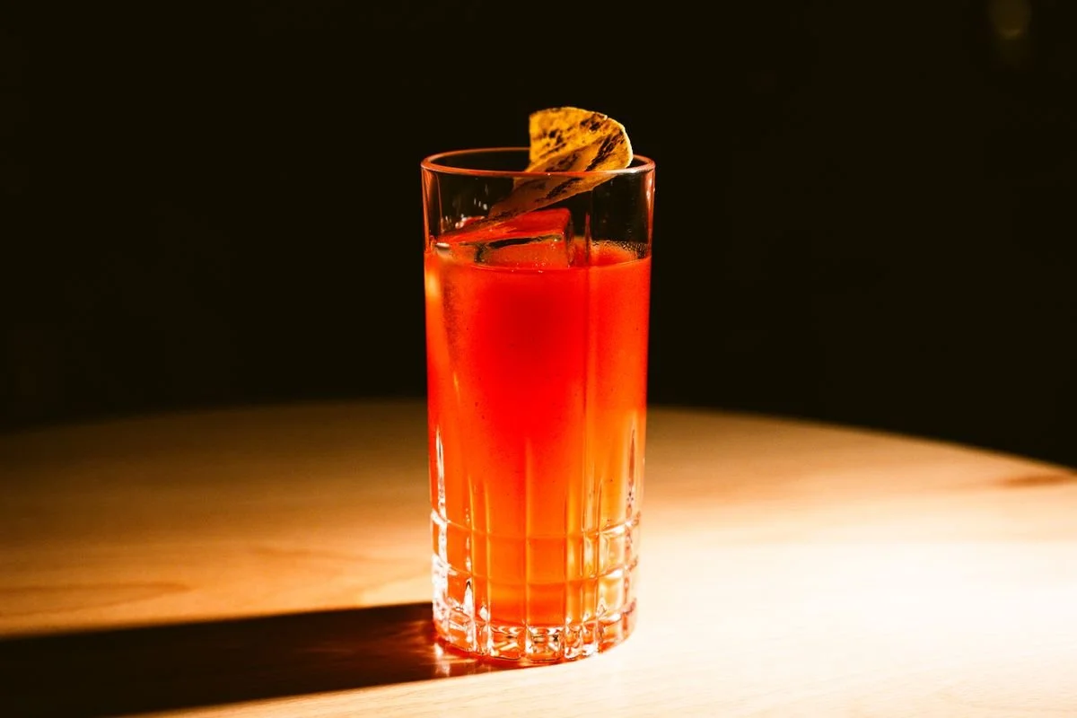 An orange cocktail sitting on a wooden table
