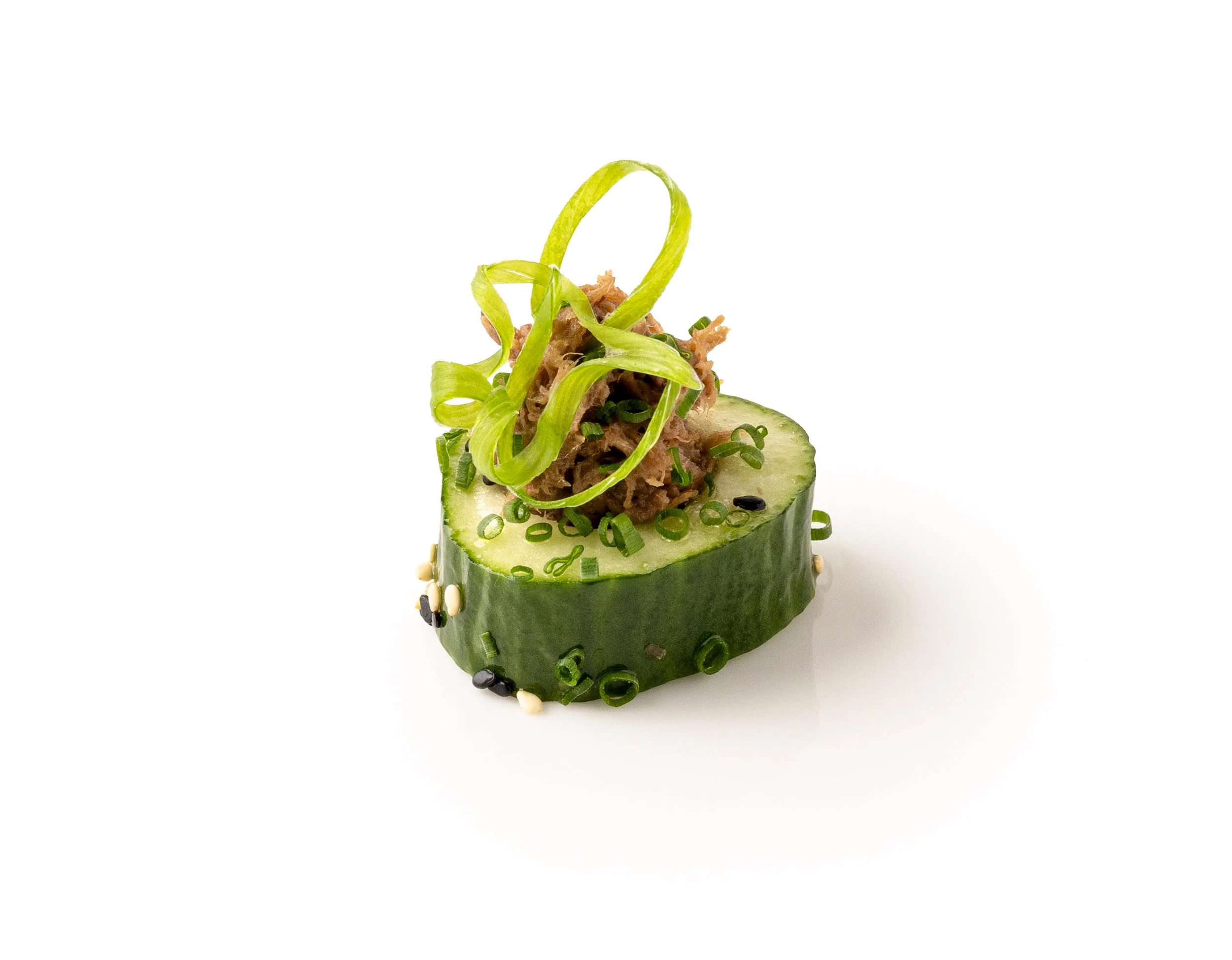 Cucumber roll with shredded tuna, sliced green onion, and decorative cucumber curls on a white background.