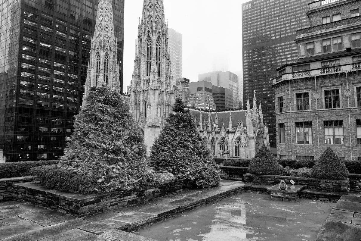 A black and white photo of a rooftop near a church