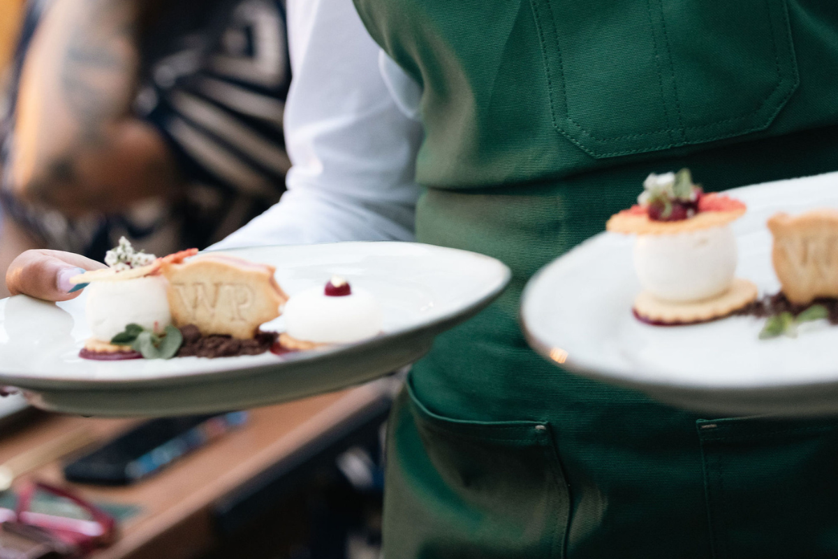 A waiter bringing food to some clients
