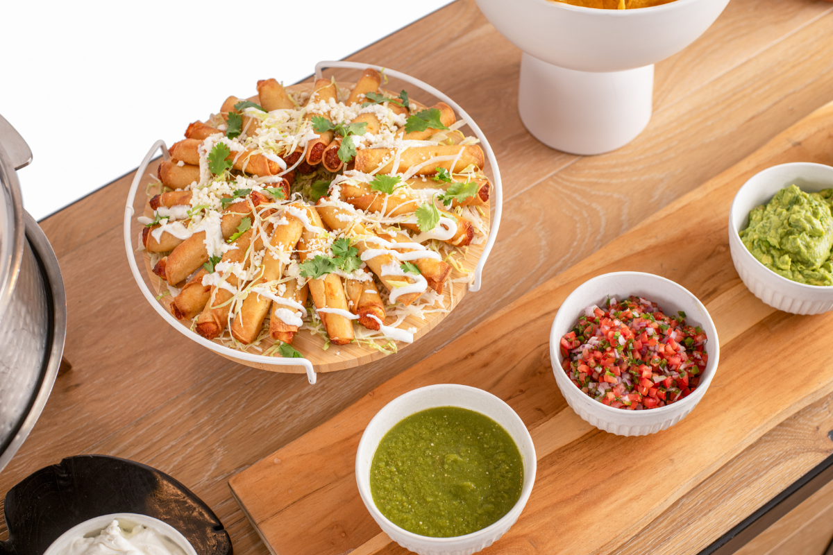 A bunch of Mexican food sitting on platters next to sauces and tomatoes