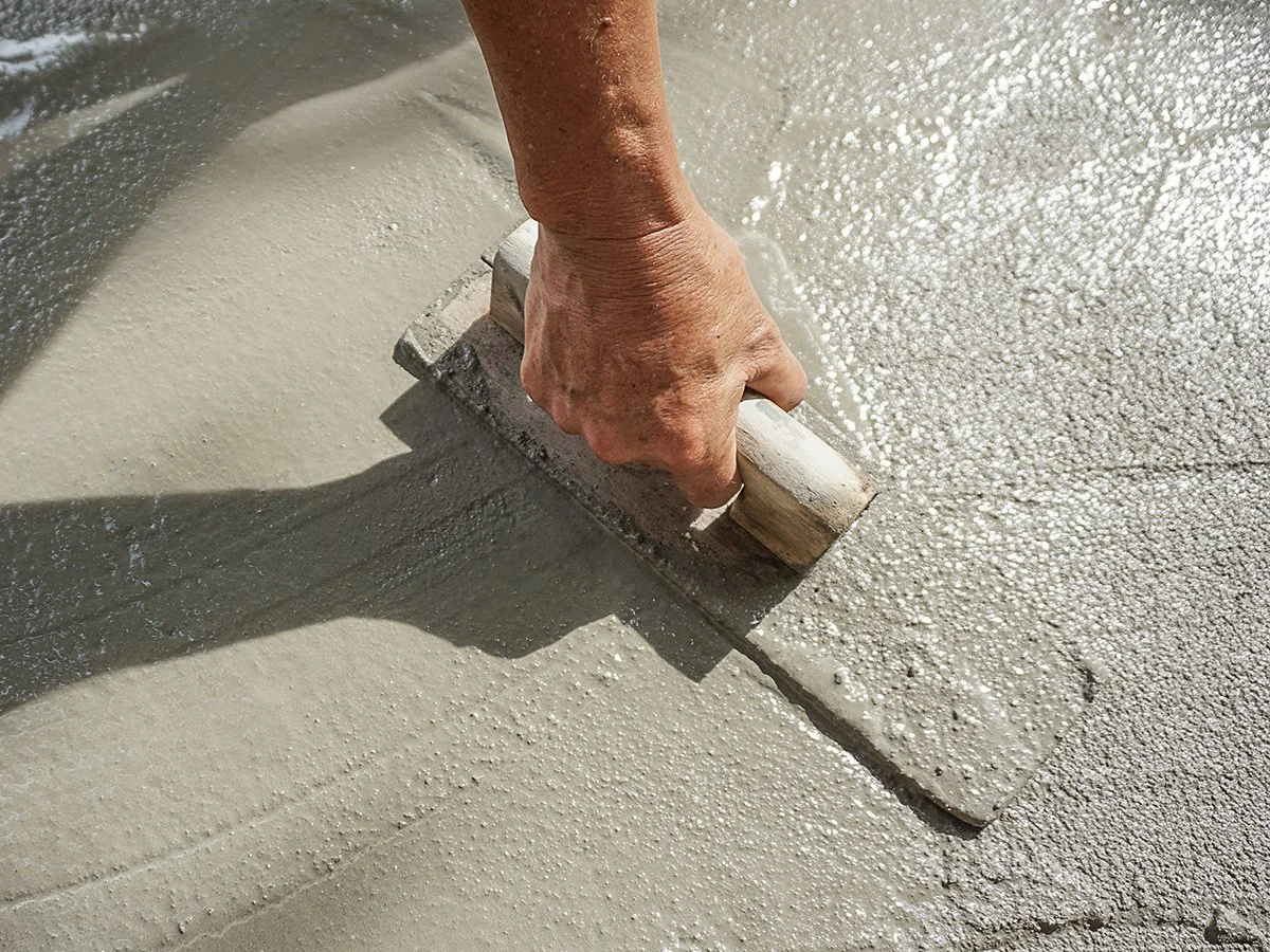 Image of a concrete worker spreading concrete to repair broken concrete.