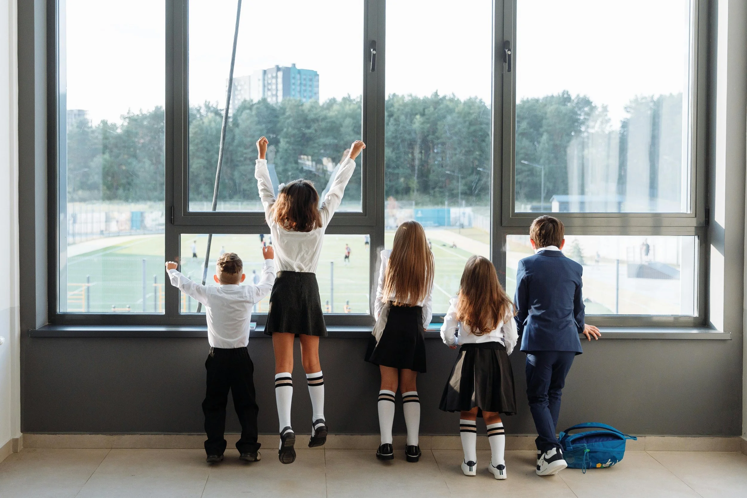 private school students in uniform looking out school window