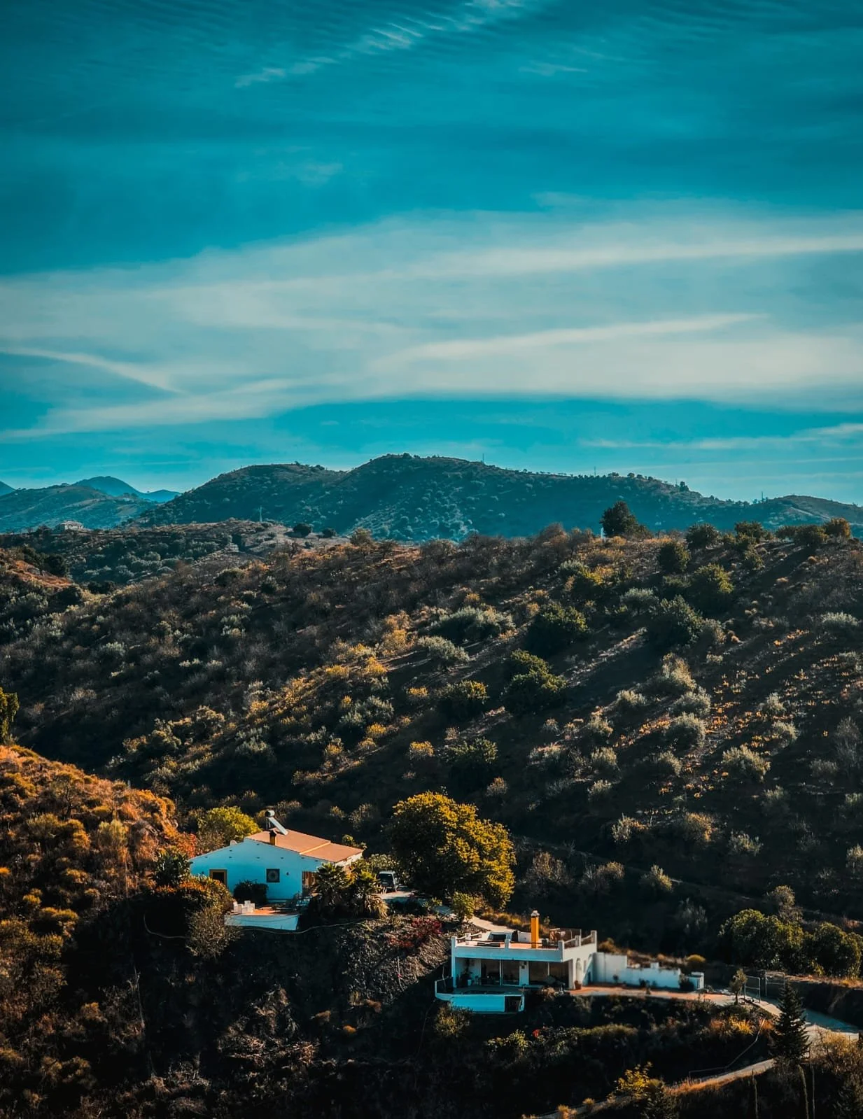 Landschaft mit Bergen, bewaldeten Hügeln und weißen Häusern im Vordergrund