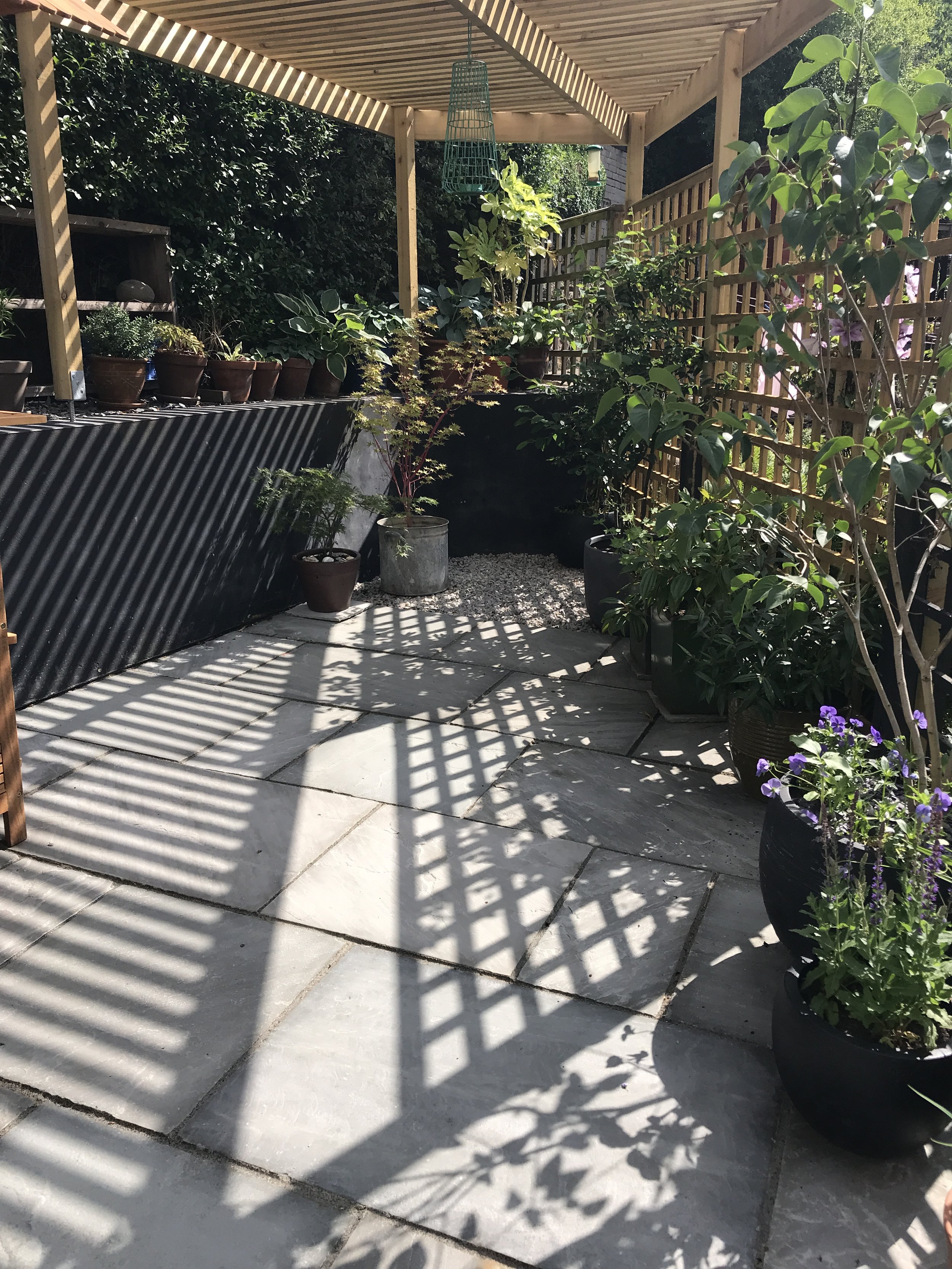 A bespoke pergola across the angled corner of the garden makes a semi-shaded dining area.