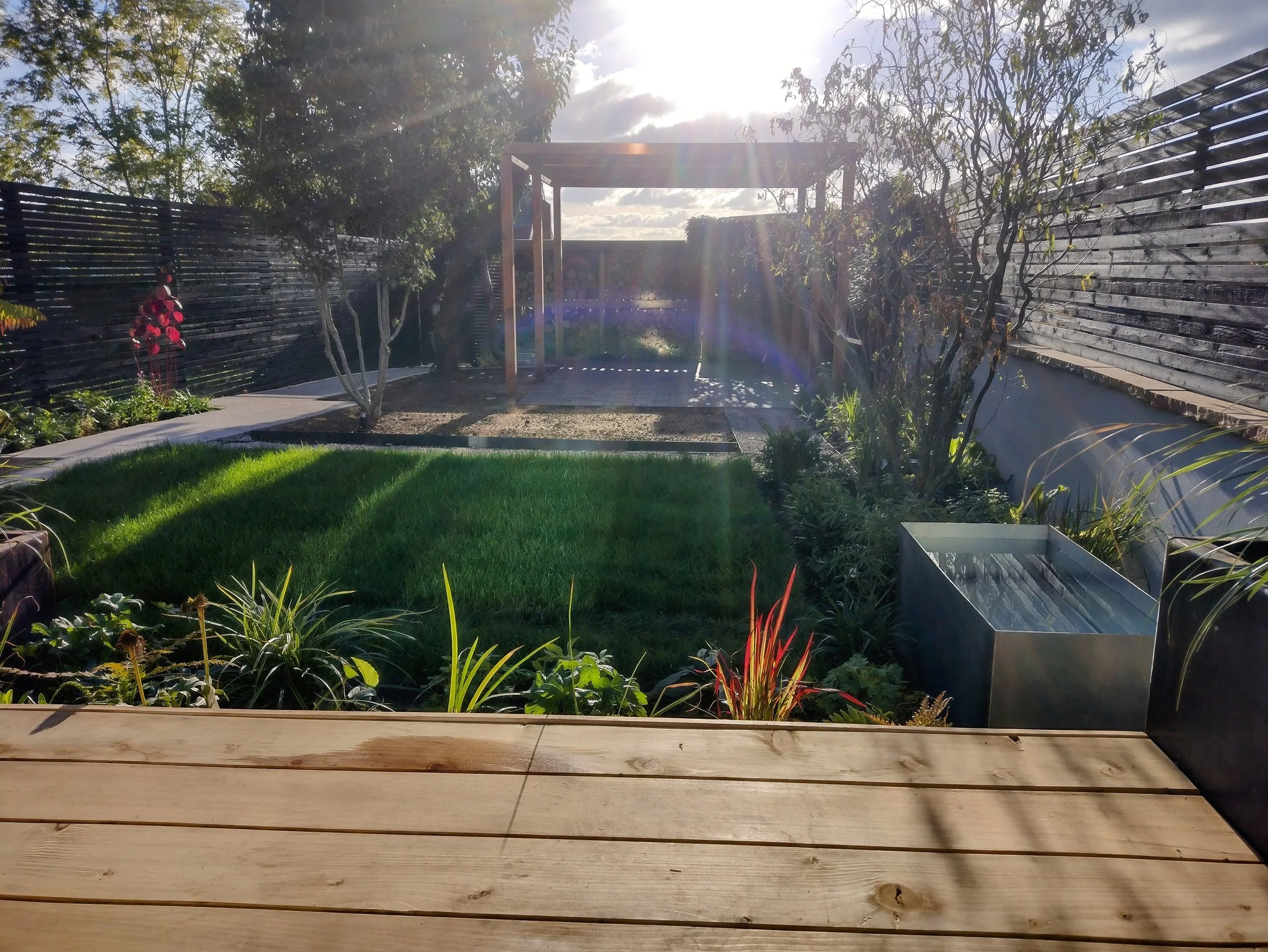 Regular planted beds makes for a busy, colourful space - features like the small galvanised pond bring peace.