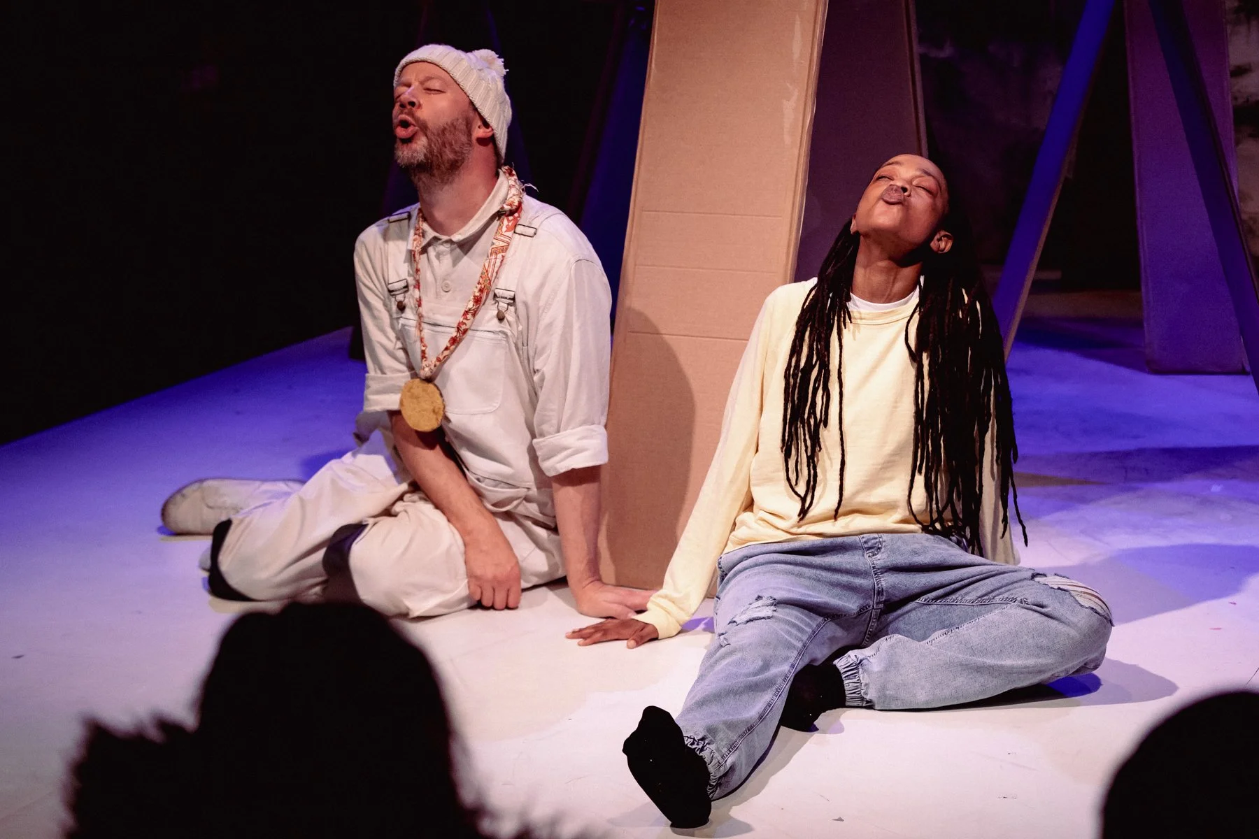 Belle and Sebastien sit on the floor looking up with mouths open howling to the sky.