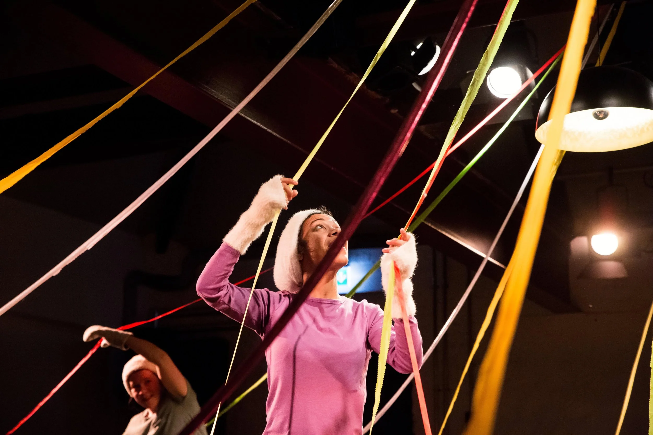 A performer looks up holding colourful ribbons.