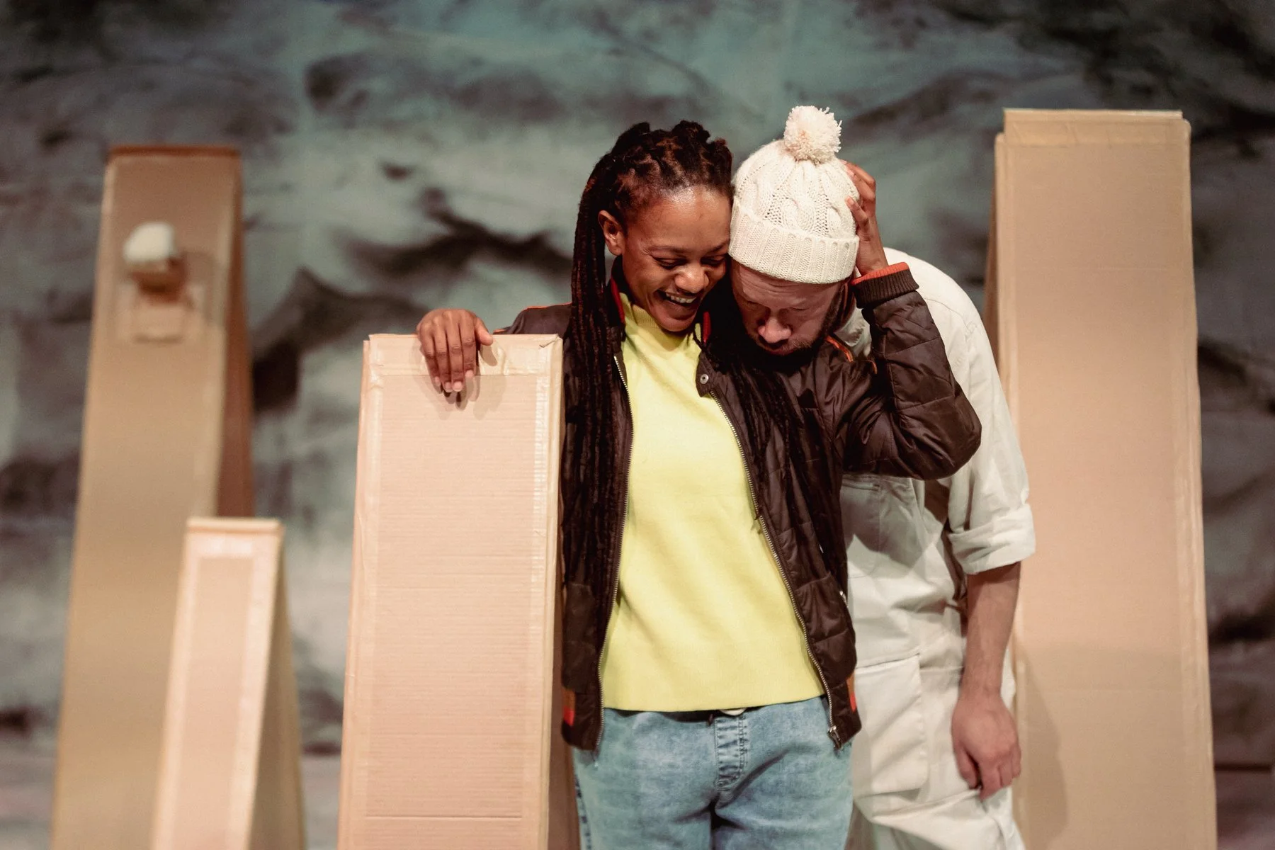 Belle rests his head of Sebastien's shoulder. They are both standing and Sebastien is smiling.