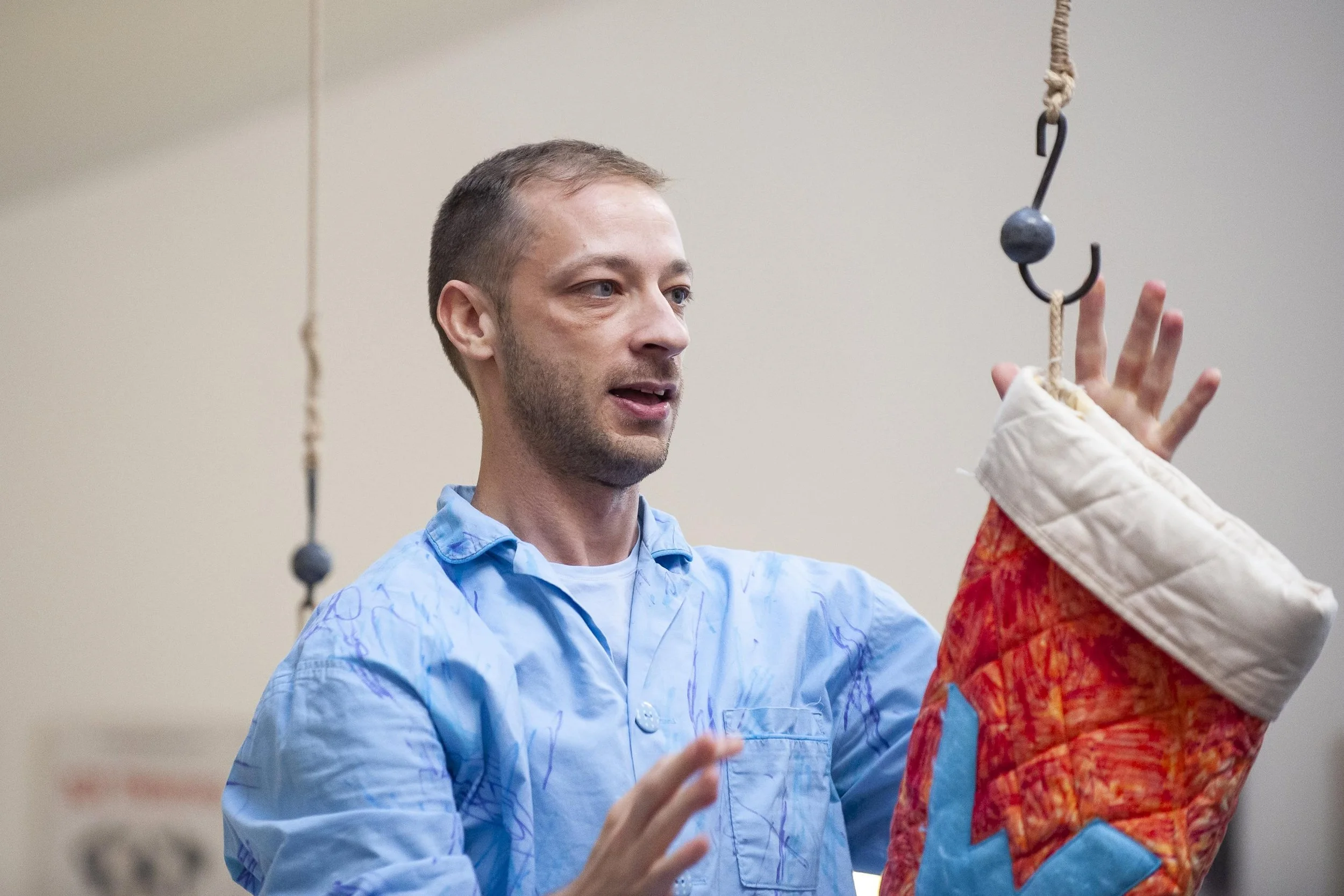 Wilkie stands looking at a large stocking which is hanging from a hook and rope from the ceiling.