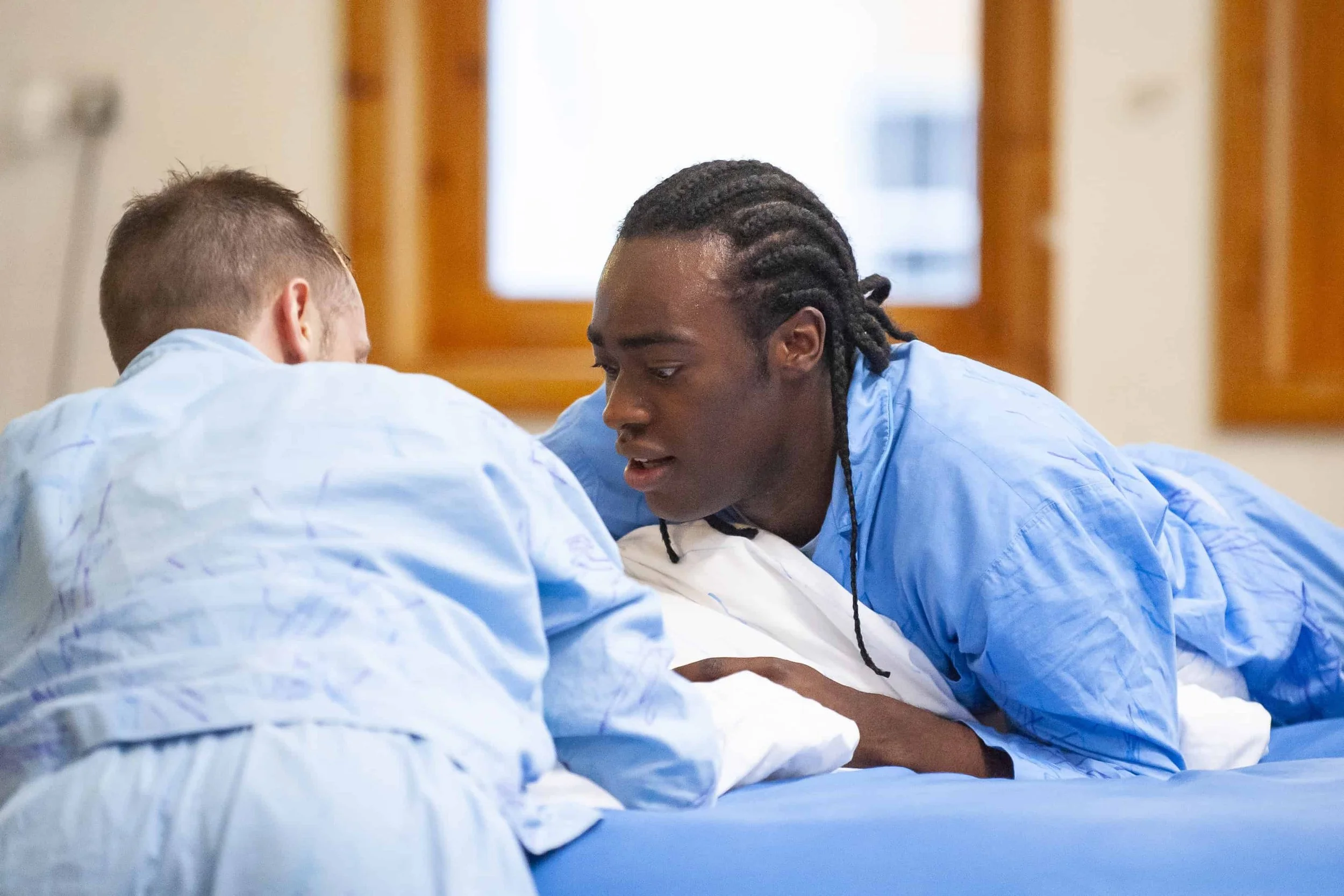 Wilkie and Kel lie on the blue mattress with a white pillow between them.