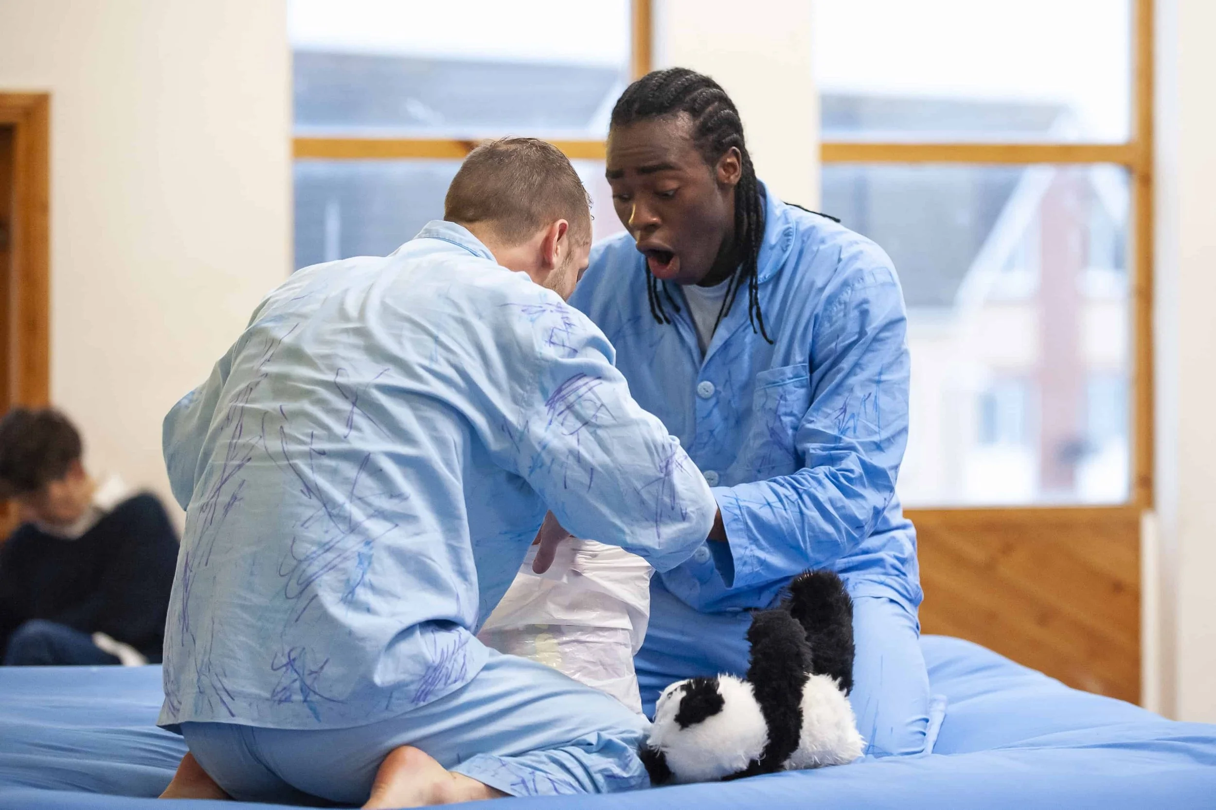 Wilkie and Kel kneel on the blue mattress looking into a pillow case in excitment.
