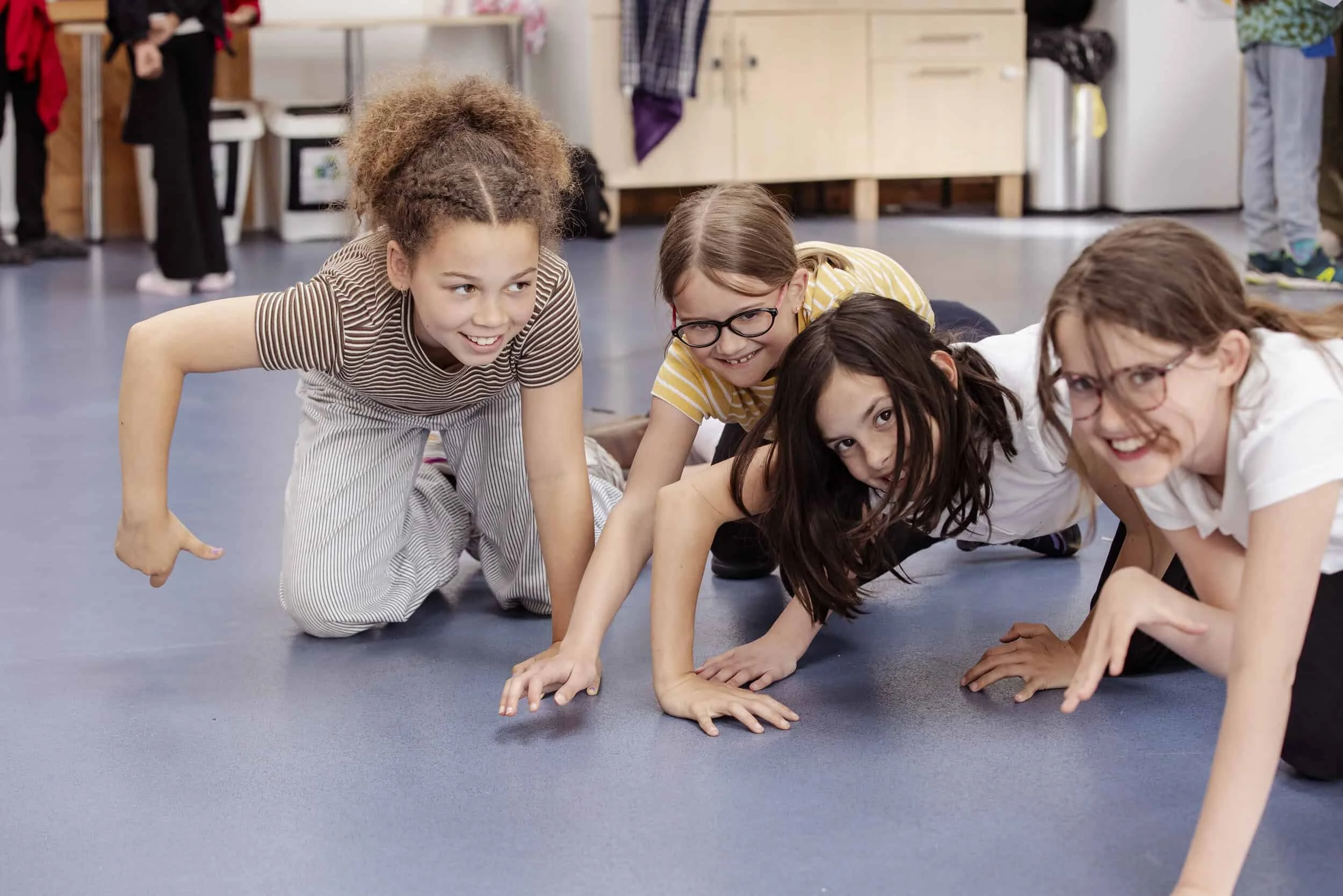 4 members of our Youth Theatre crouch on the floor looking towards the camera.