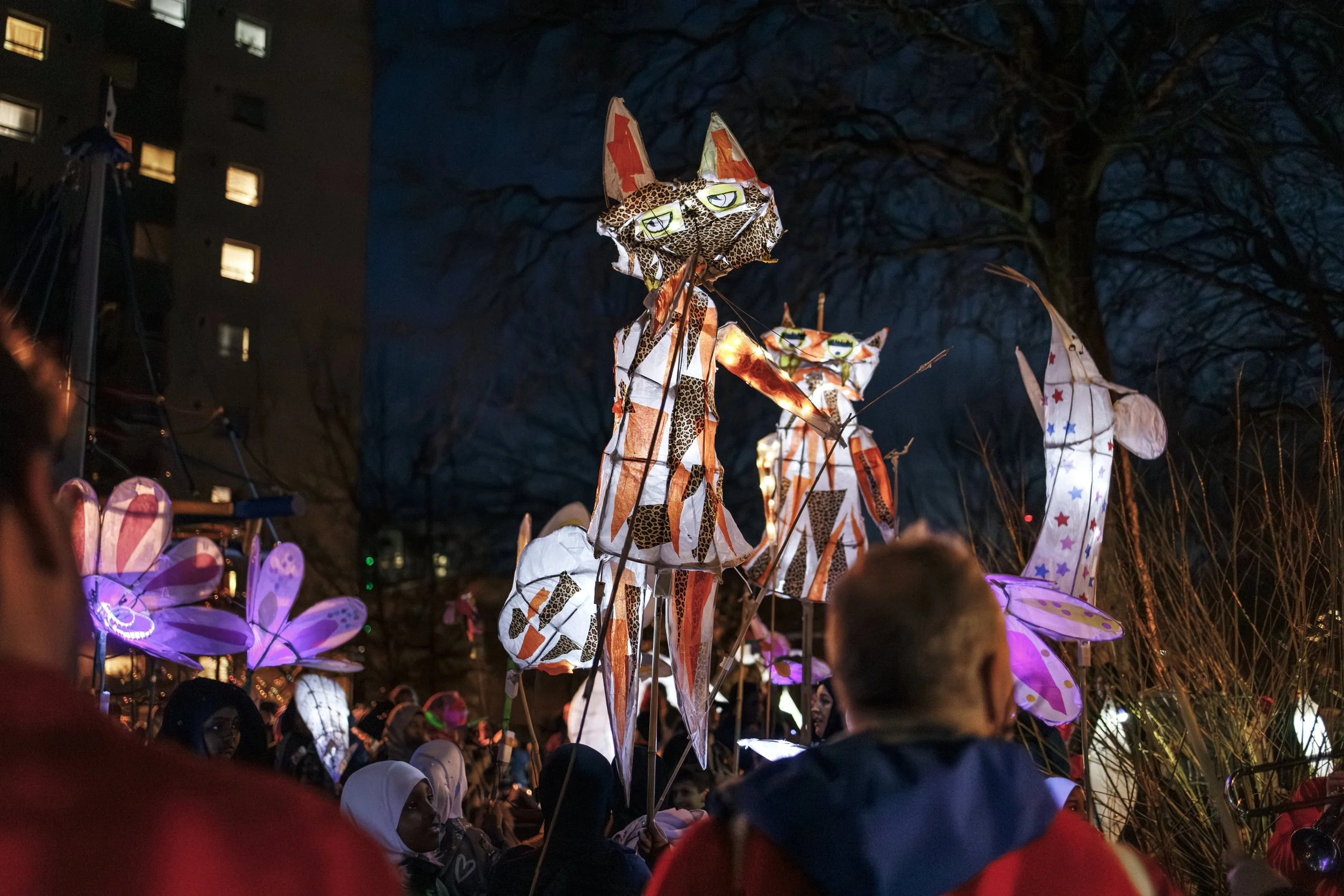 People gather outdoors at night to see illuminated urban animal-shaped lanterns during Winter Lights.