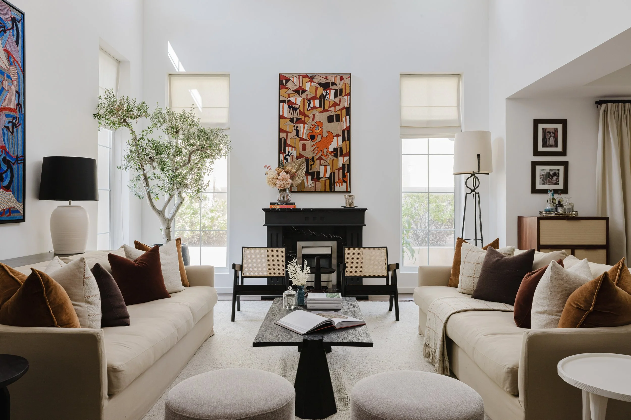 Modern luxury living room interior with high ceilings, neutral furniture, fireplace, artwork, and natural light photographed for interior architecture photography