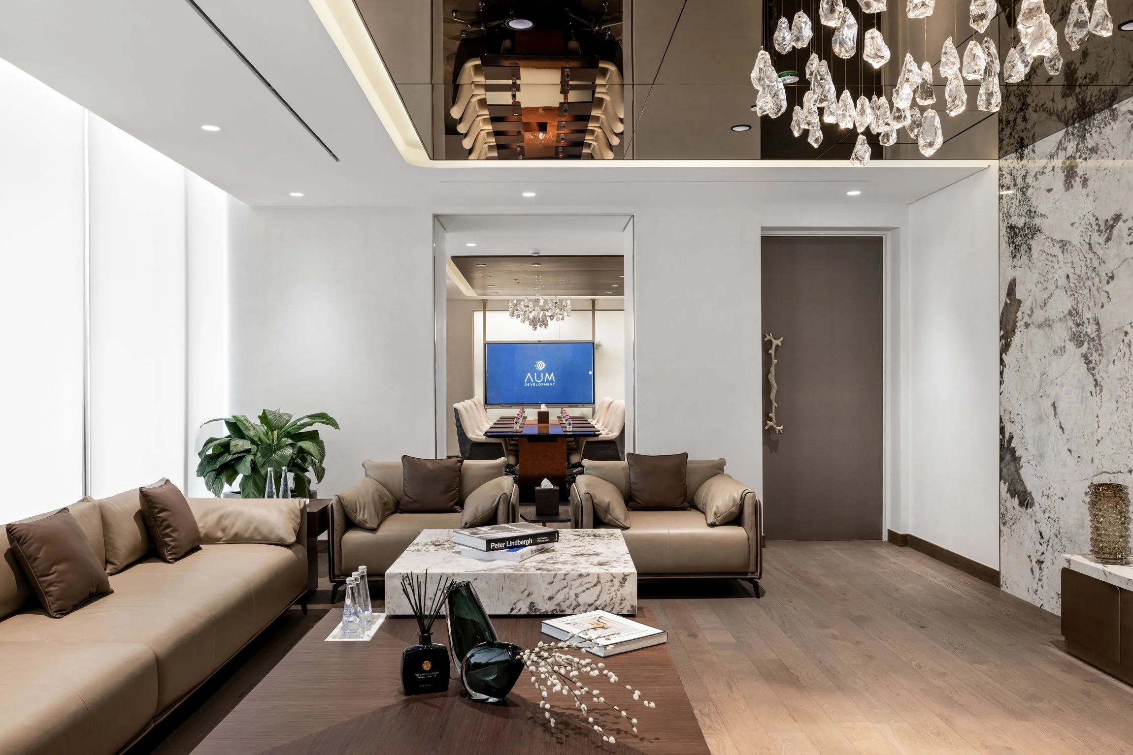 Luxury office lounge photography in Dubai featuring bespoke furniture, stone finishes, statement lighting and a contemporary boardroom beyond.
