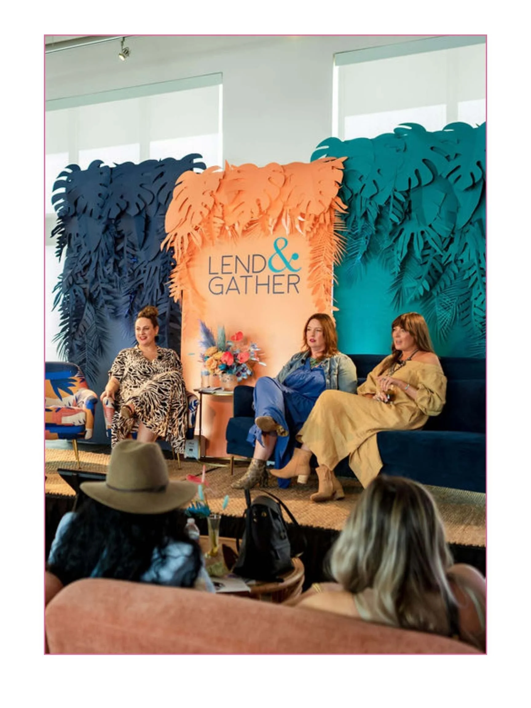 Women sitting on a stage at a panel discussion with a backdrop that reads "Lend & Gather" and a tropical leaf design.