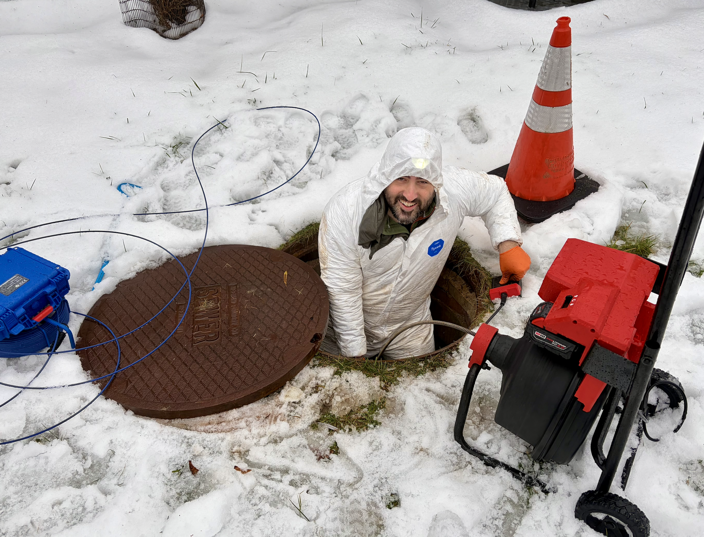 Using a drain snake to bust through a major clog that was causing a backup. We got it!