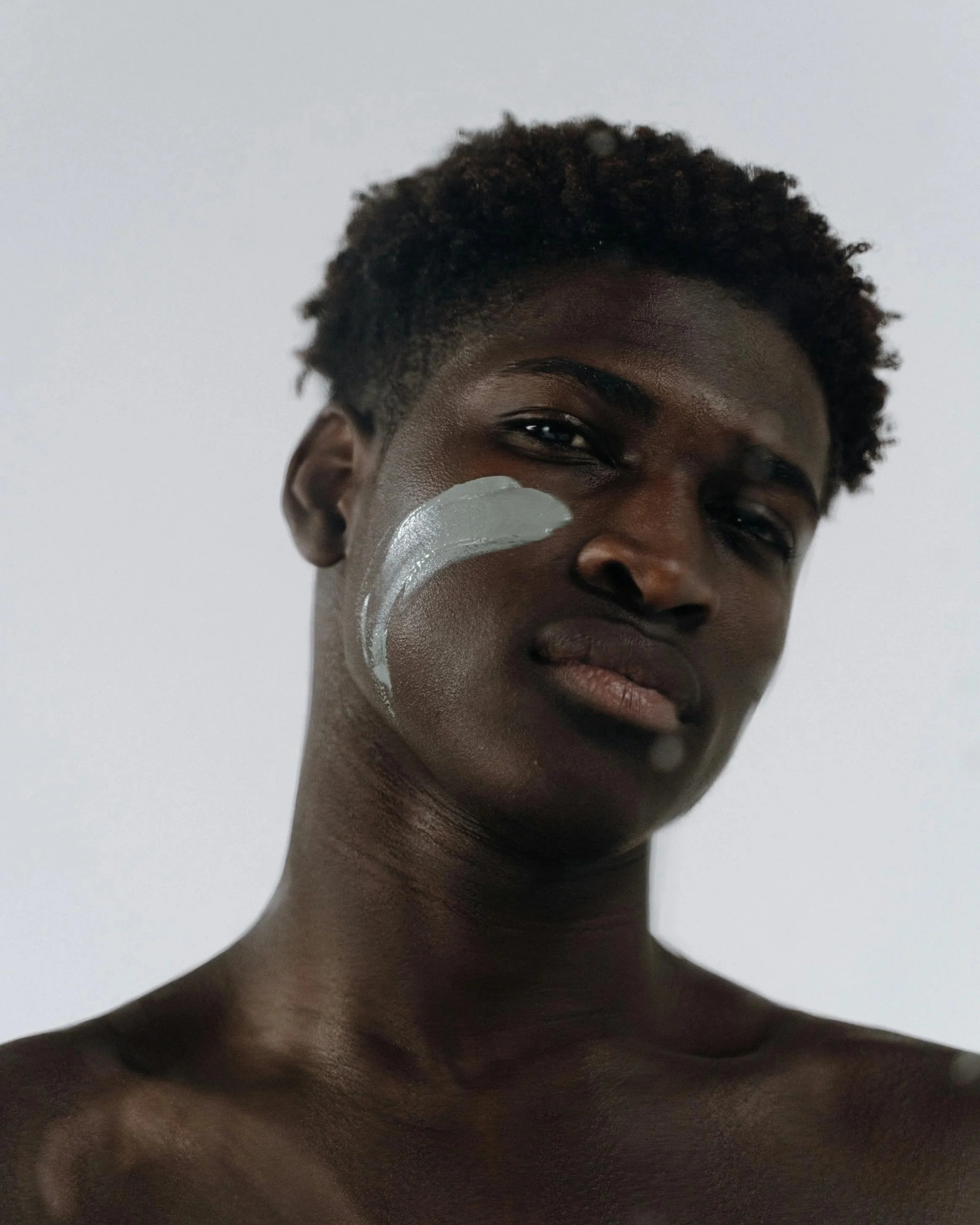 Image of Male Model with a swatch of skincare on cheek.