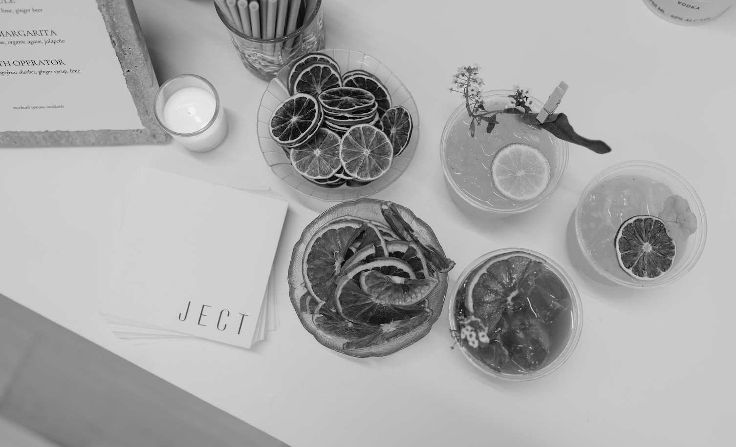 Black and White image of a table with napkins, drinks, candle, orange slices