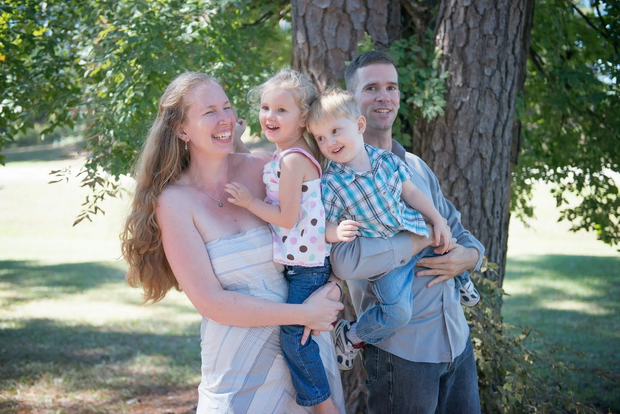 Smiling family with two young children enjoying time outdoors, reflecting the family-centered values of Play to Say Therapy in Dumfries, VA