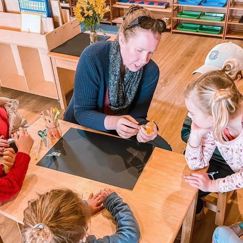 Speech-language therapist leading a small group activity with elementary-age children, representing social communication and group therapy services at Play to Say Therapy