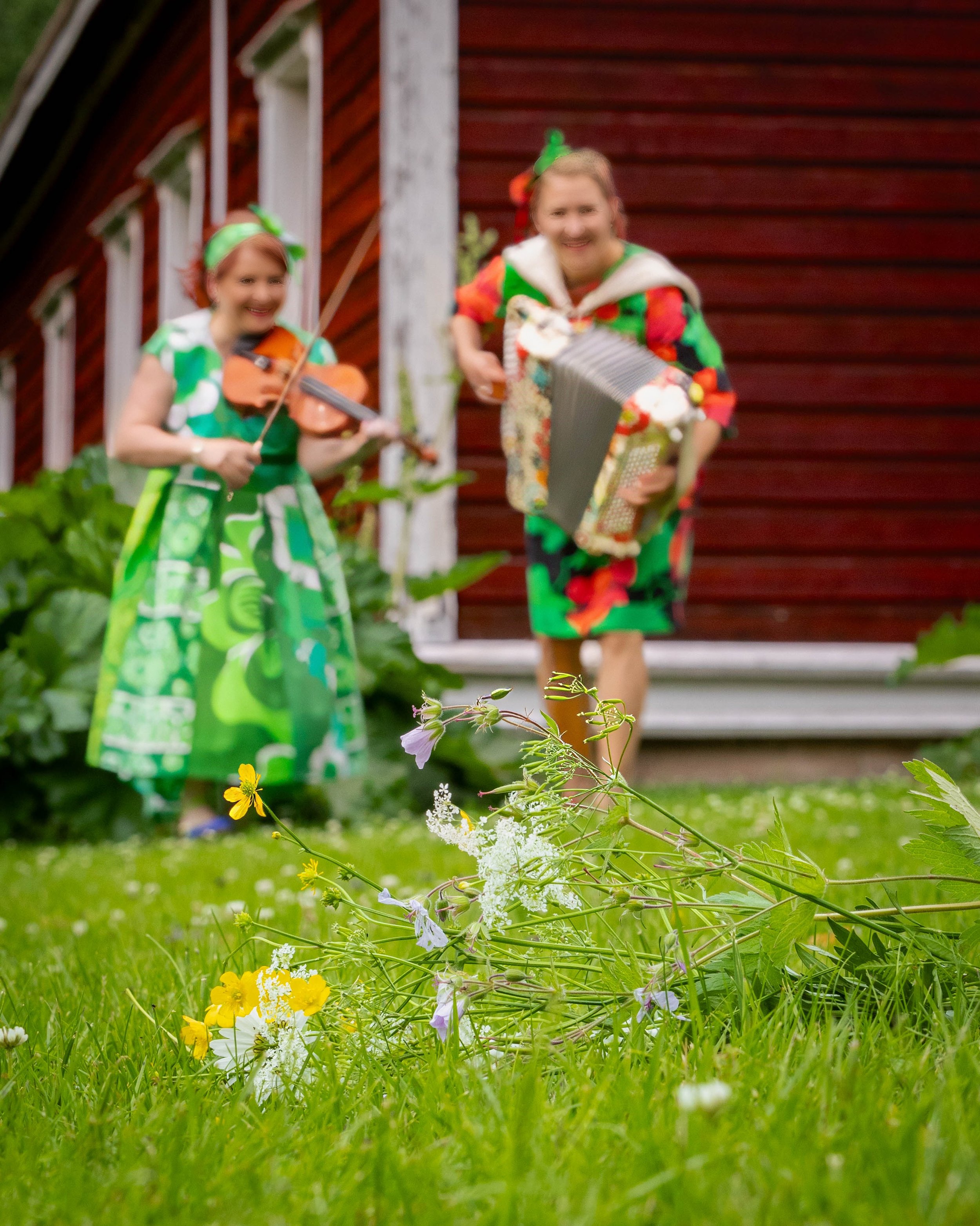 Duo Petra & Riitta esiintyy iloisesti kesäauringossa, jossa viulun ja haitarin sävelet yhdistyvät tanssiin ja luonnon värikkyyteen.