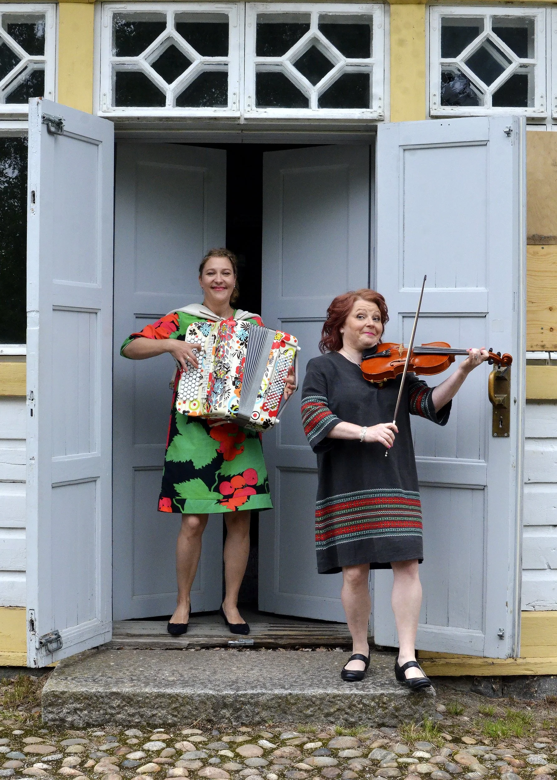 Duo Riitta & Petra soittaa viulu- ja harmonikkamusiikkia Pöljän Pysäkin edustalla. Esityksen lämmin ja harmoninen ilmapiiri yhdistyy historialliseen miljööseen, luoden ikimuistoisen hetken yleisölle.