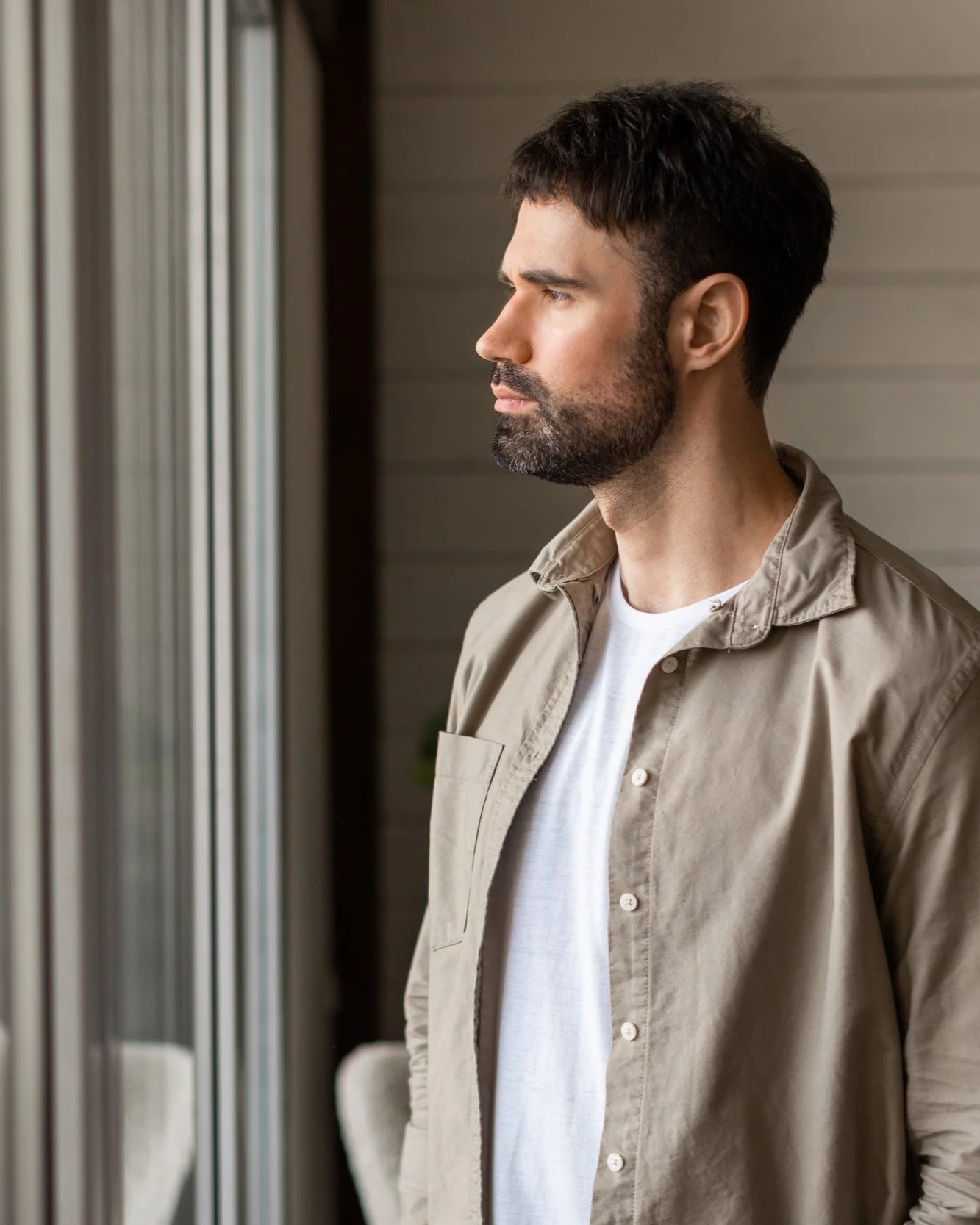 Profile profile of a man with dark hair and beard looking out a window