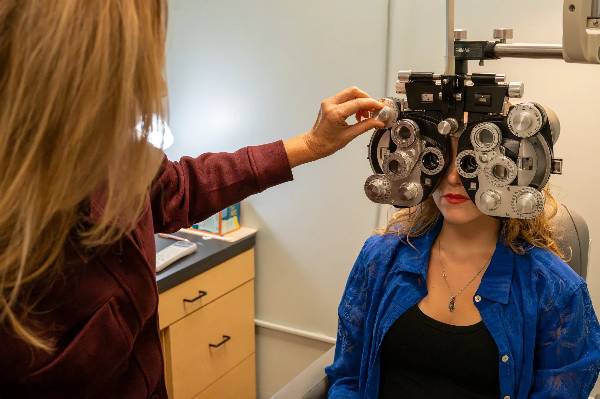 Dr. Mabie performing a refraction eye exam on her daughter Audra using a phoropter to determine an eyeglass prescription.