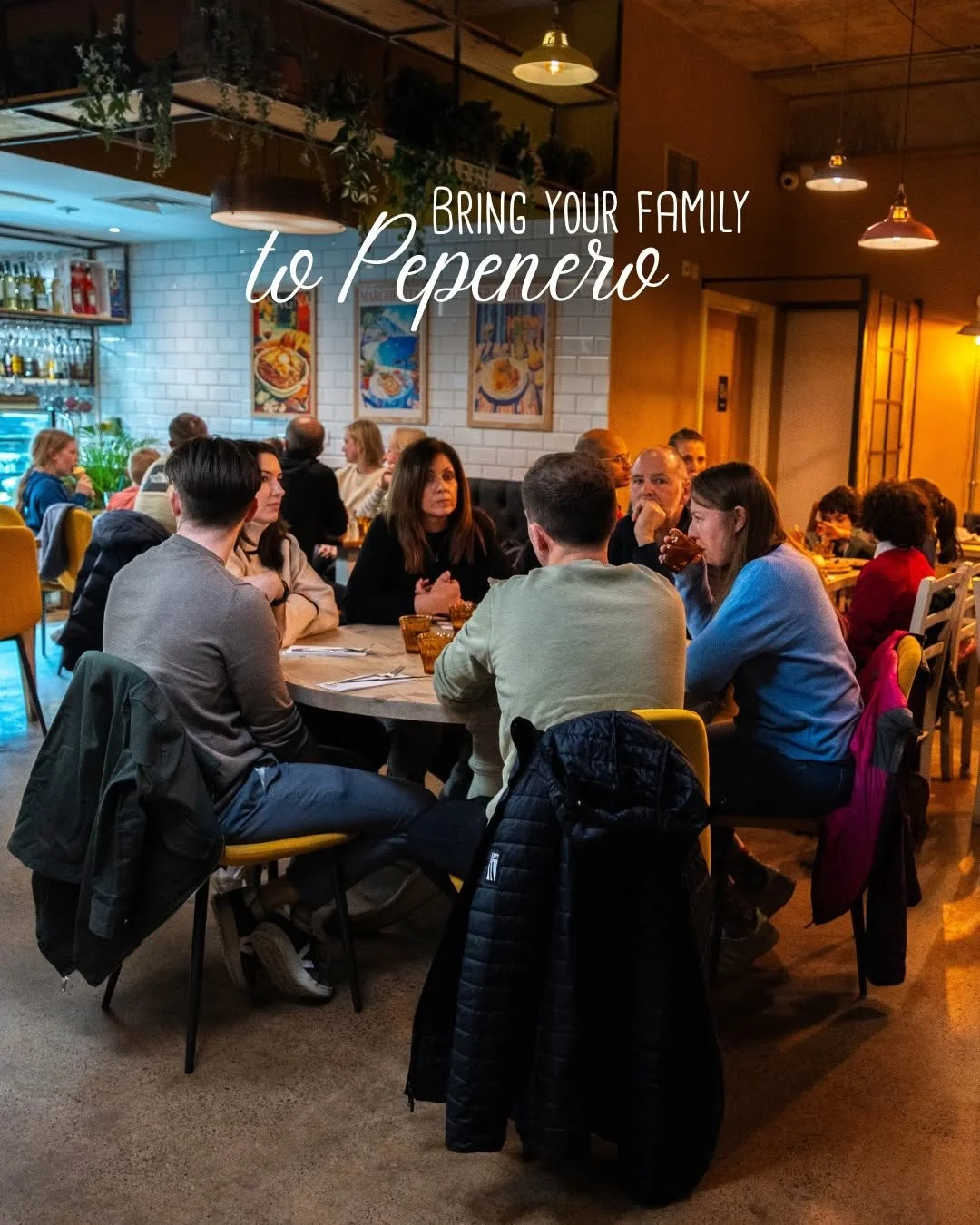 Group of people dining together at a restaurant, with a sign that says "Bring your family to Pepenero."