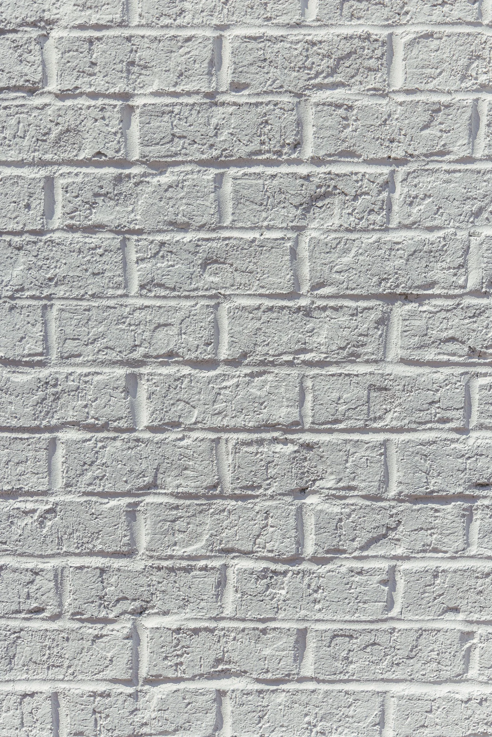 White painted brick wall with textured surface and horizontal mortar lines.