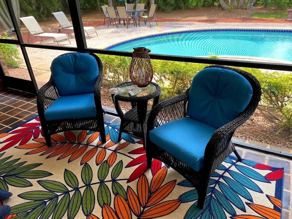 Hand-crafted vibrant blue outdoor patio chair cushions paired with a matching tropical leaf pattern outdoor rug, perfectly designed for durable comfort in a South Florida pool patio enclosure.