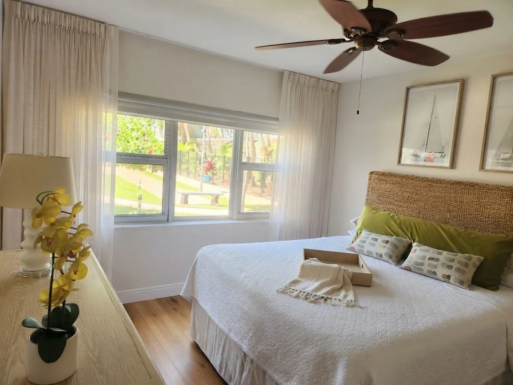 Light and airy custom sheer drapes framing a sunlit bedroom window with serene outdoor views, custom-crafted by London Stitchery.