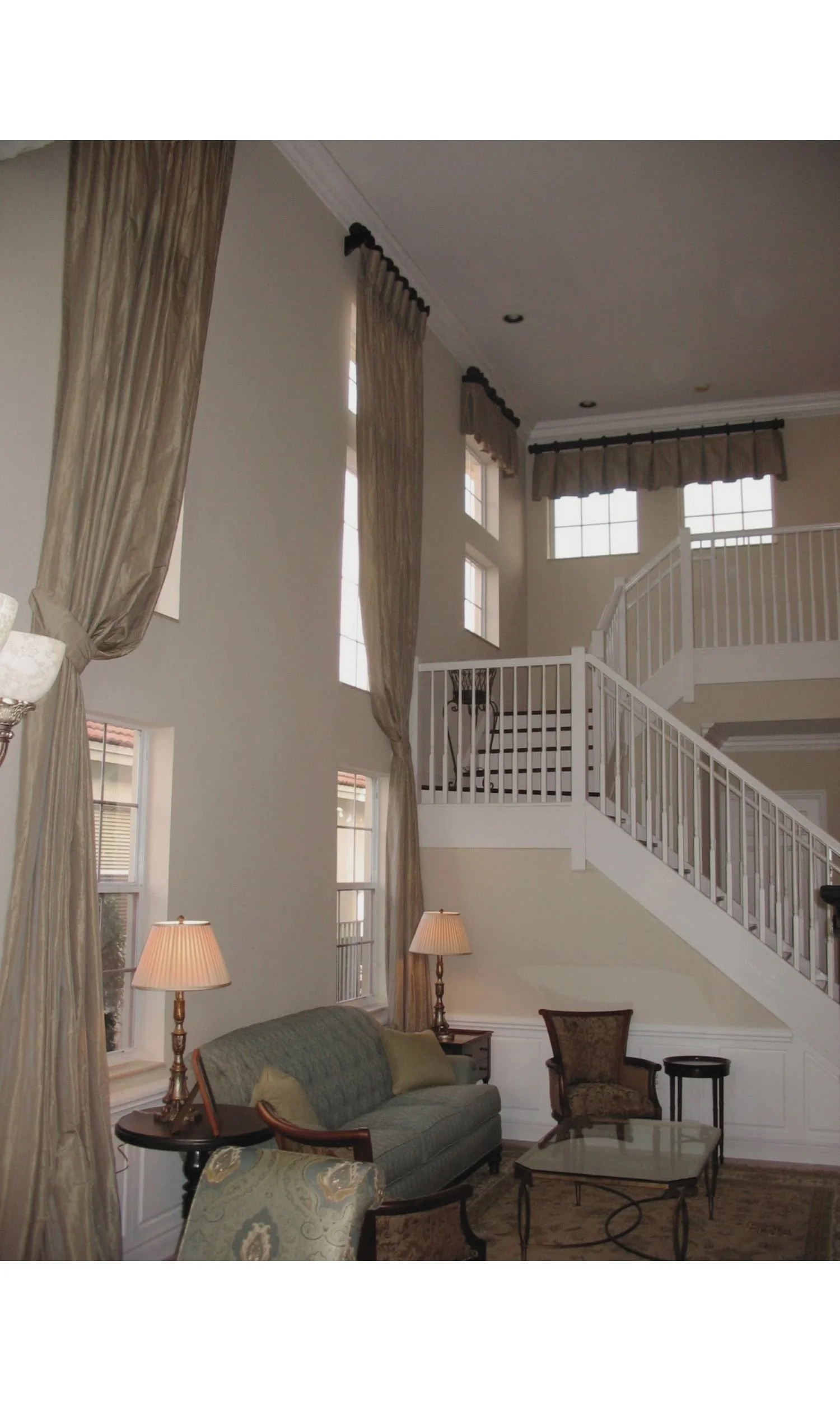 Two-story custom silk drapery featuring engineered champagne flute headings and elegant box-pleated valances on decorative wooden rods.