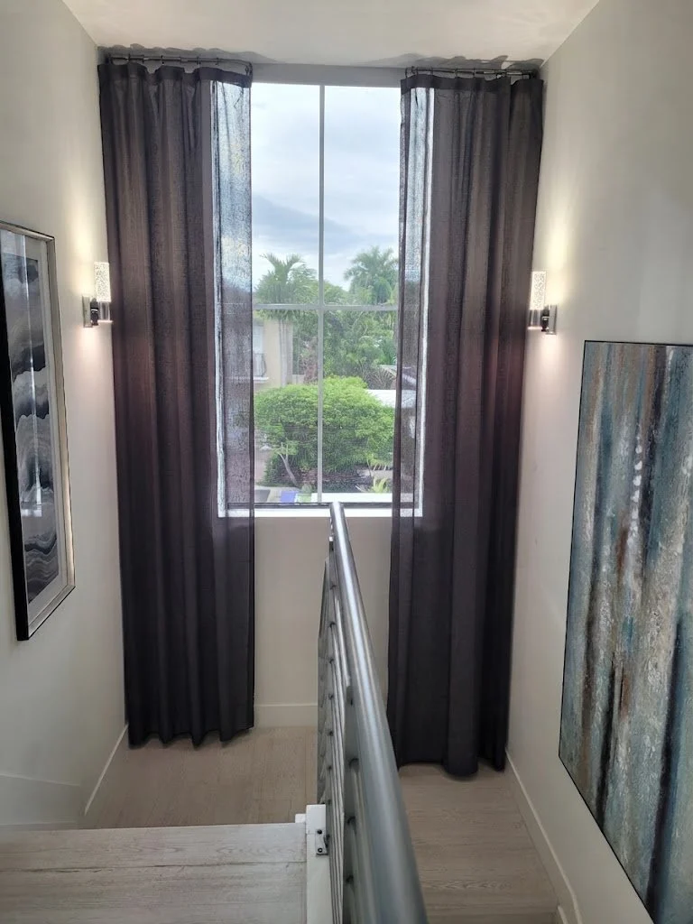 Elegant full-length dark draperies gracefully framing a tall staircase window, custom-fabricated by London Stitchery.