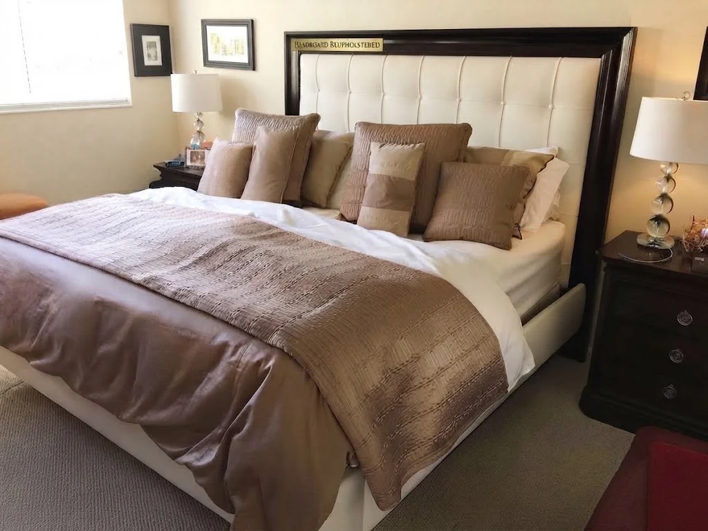 Luxurious custom dark-toned bedding suite accented with a rich combination of decorative toss pillows and a structured tufted headboard, showcasing sophisticated craftsmanship.