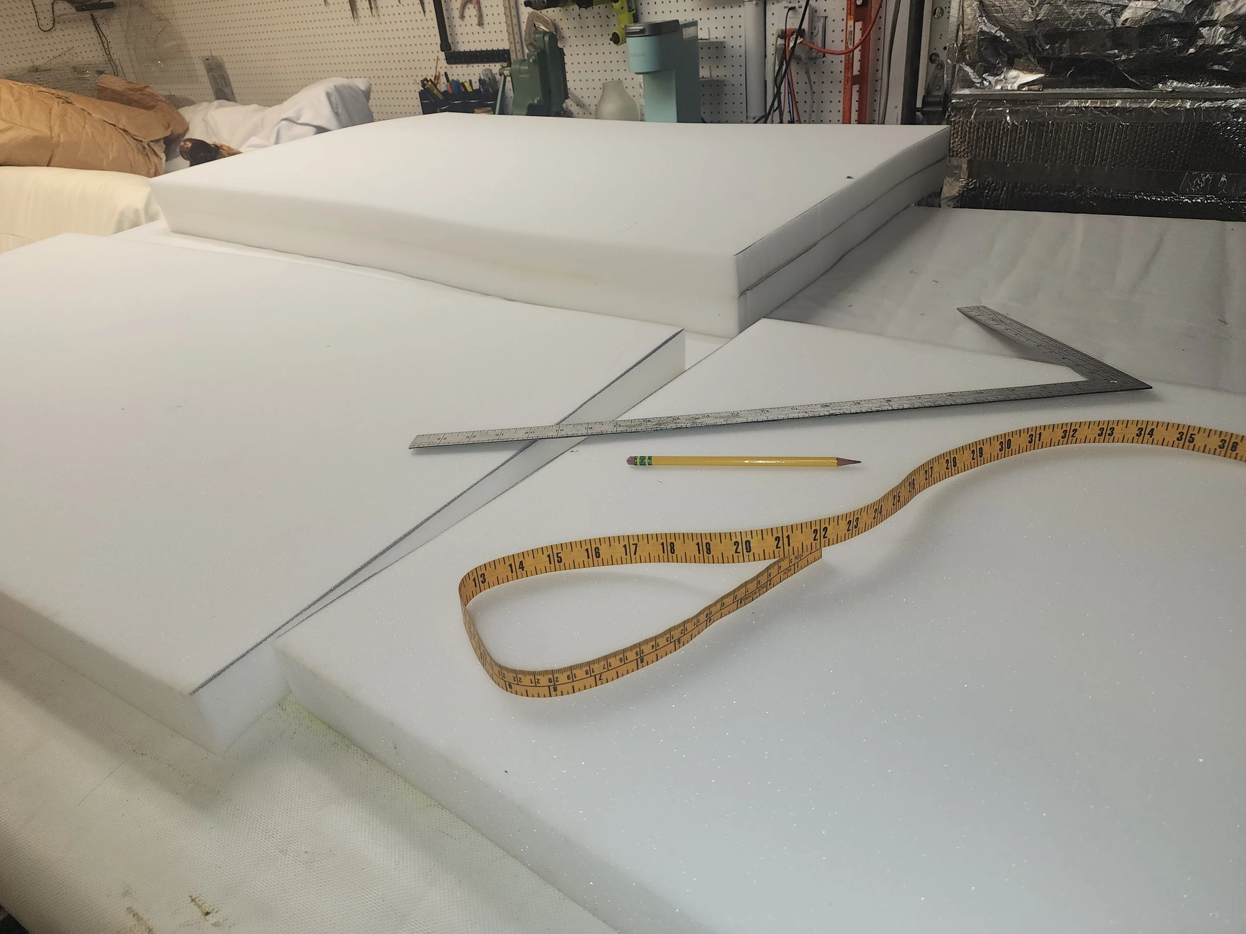 Custom upholstery foam, shears, and measuring tape laid out in the workroom.