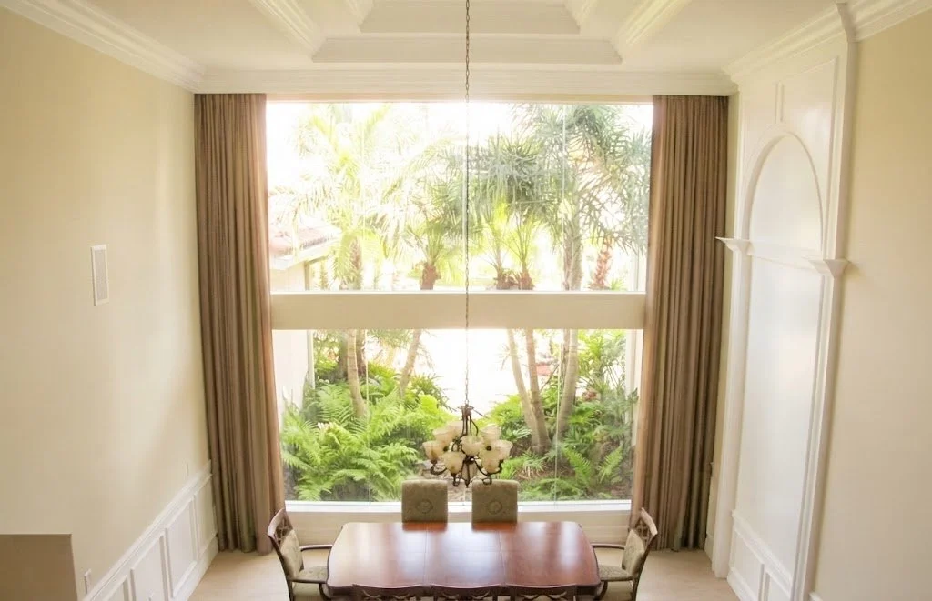Custom full-length stationary drapery panels framing a dramatic two-story dining room window, custom-fabricated by London Stitchery.