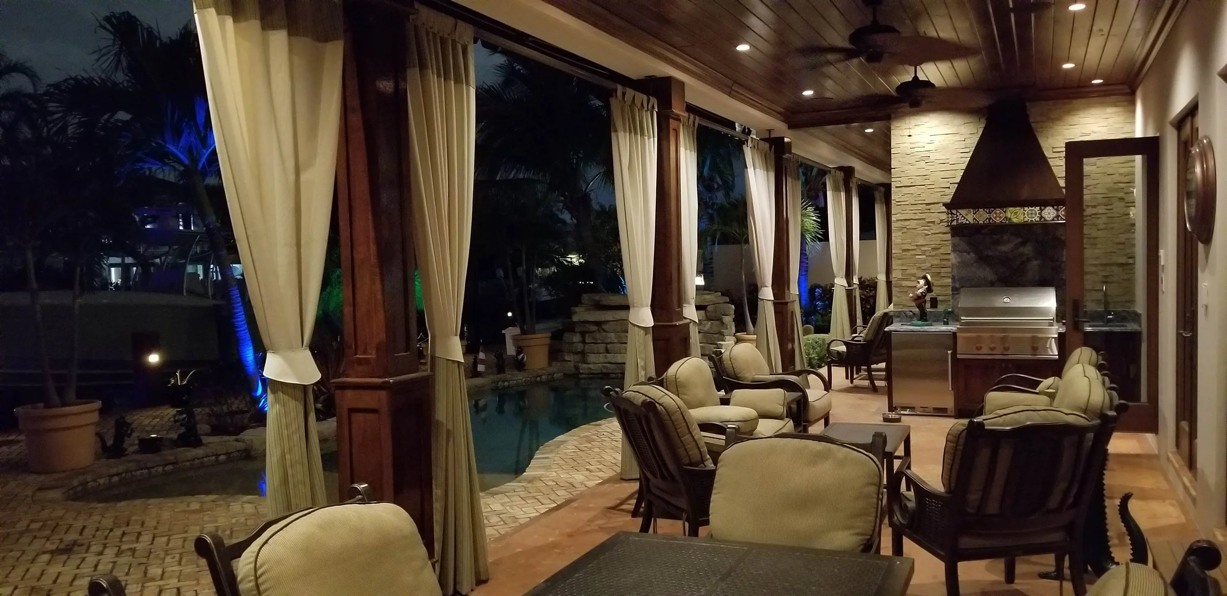 Outdoor custom-made stationary drapes framing a poolside view.