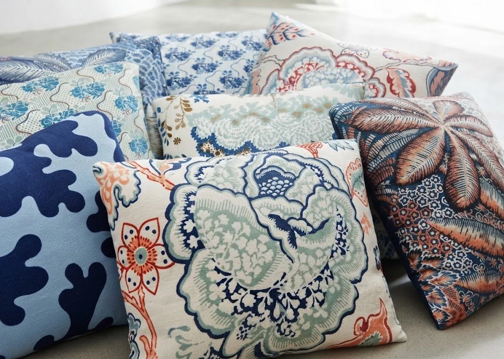 An assortment of luxury decorative pillows featuring vibrant blue and terracotta botanical prints with knife-edge tailoring, custom-made by London Stitchery.