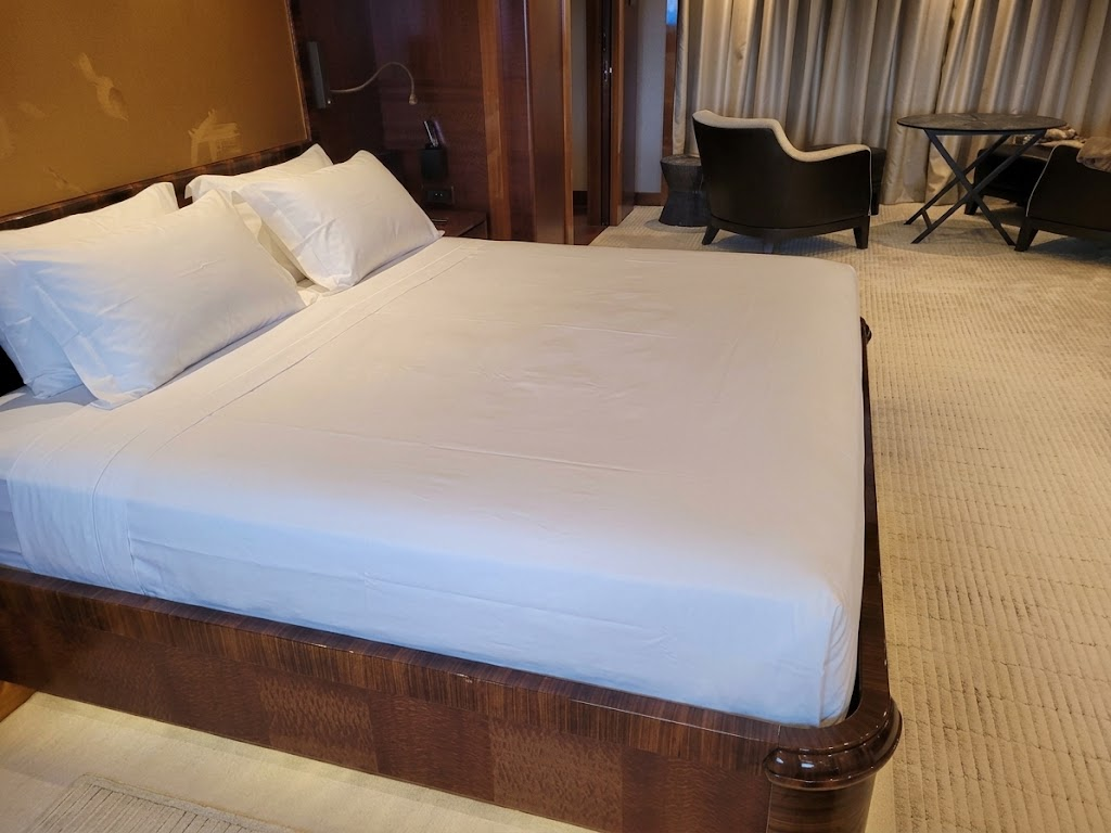 Custom king-size master cabin bed on a luxury yacht featuring freshly tailored white fitted sheets handcrafted to fit the unique mattress shape, created by London Stitchery in Fort Lauderdale.