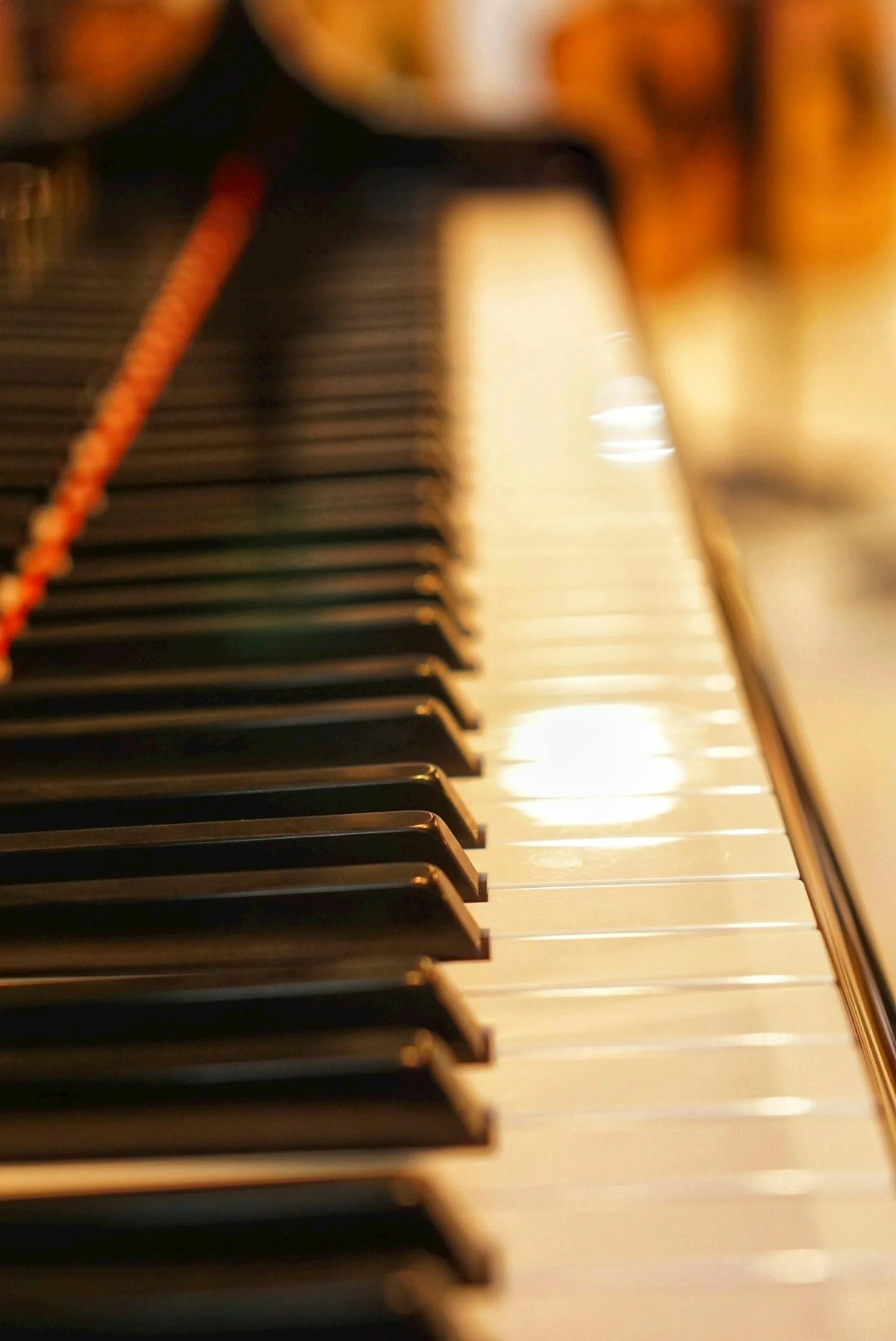 Close-up view of piano keys with a warm lighting, showing black and white keys in a diagonal perspective.