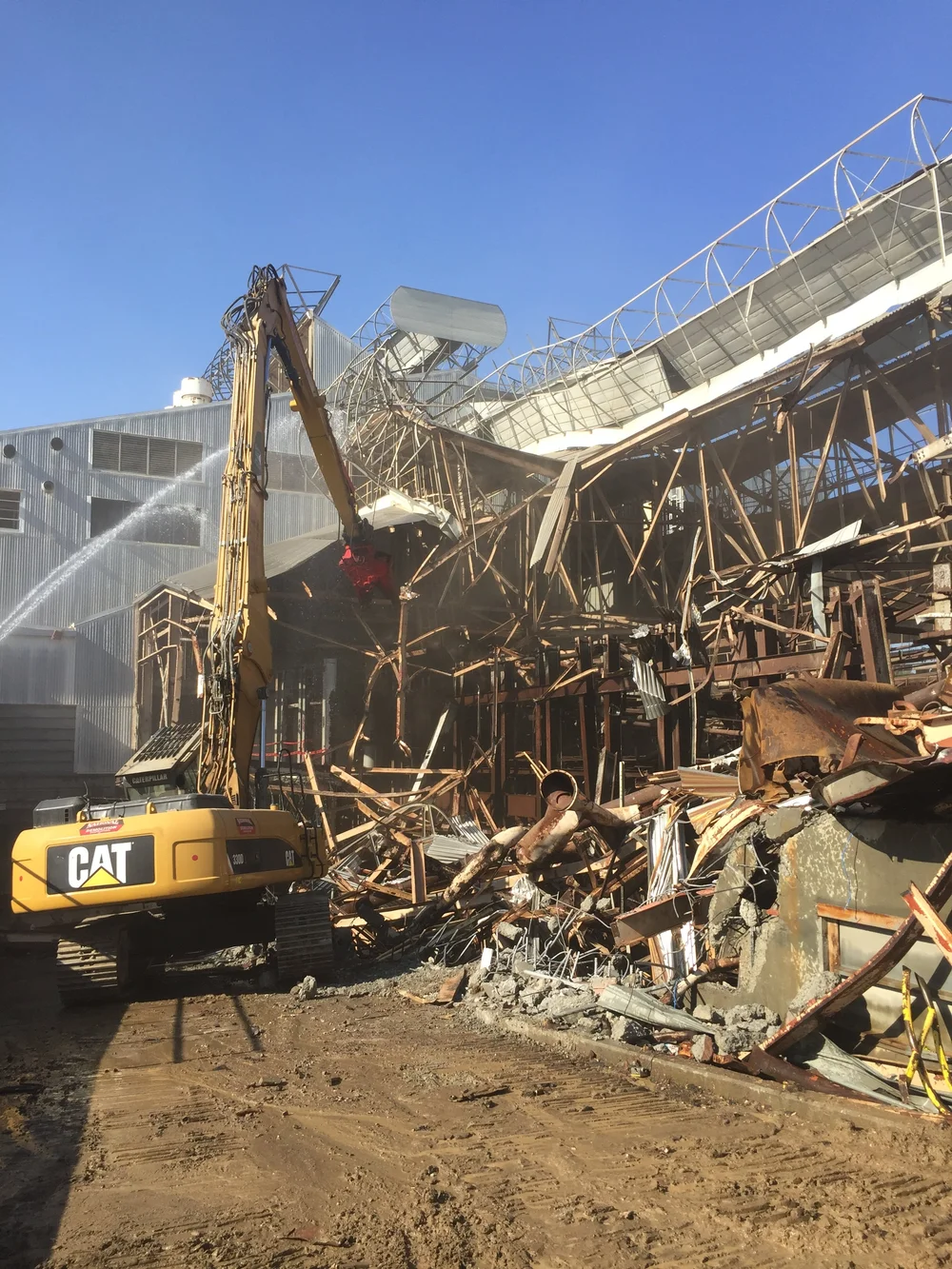 Excavator working beside a partially demolished structure